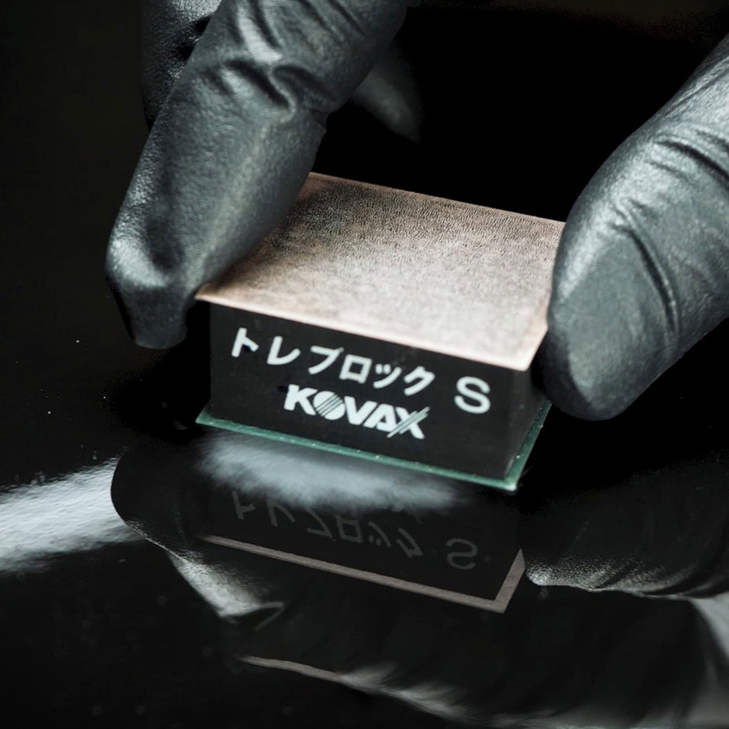 Kovax tolecut held by gloved hands sanding on a reflective clear coated surface