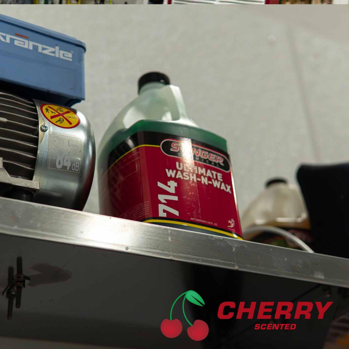 Stinger Chemical Ultimate Wash-N-Wax 714 cherry scented soap on a shelf next to a pressure washer