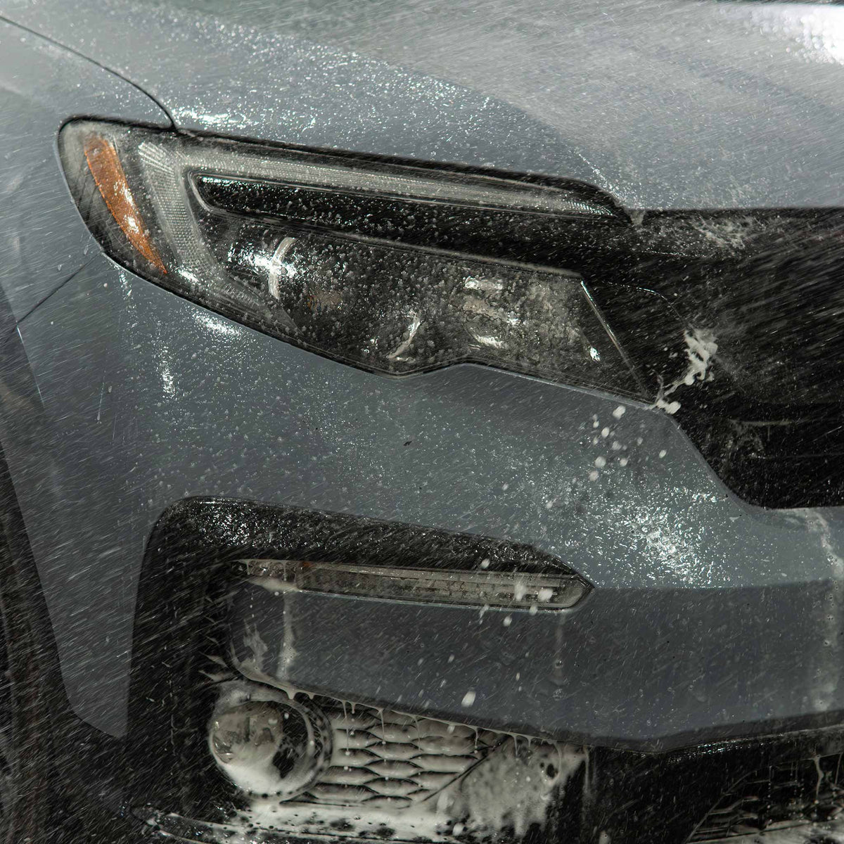Stinger Chemical Ultimate Wash-N-Wax 714 rinsing off a headlight and bumper as water sheets away