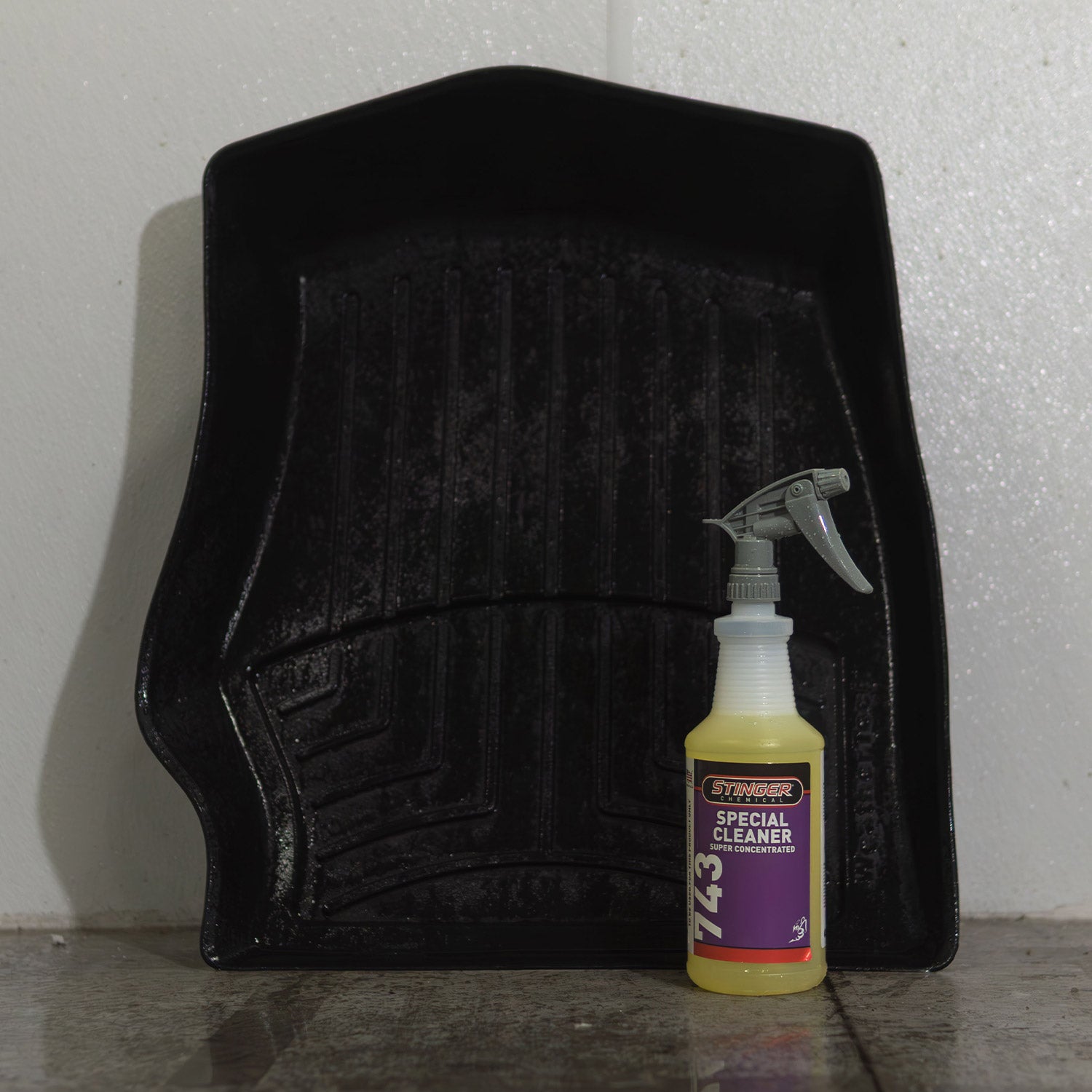 Black car mat with a bottle of Special Cleaner on a gray surface