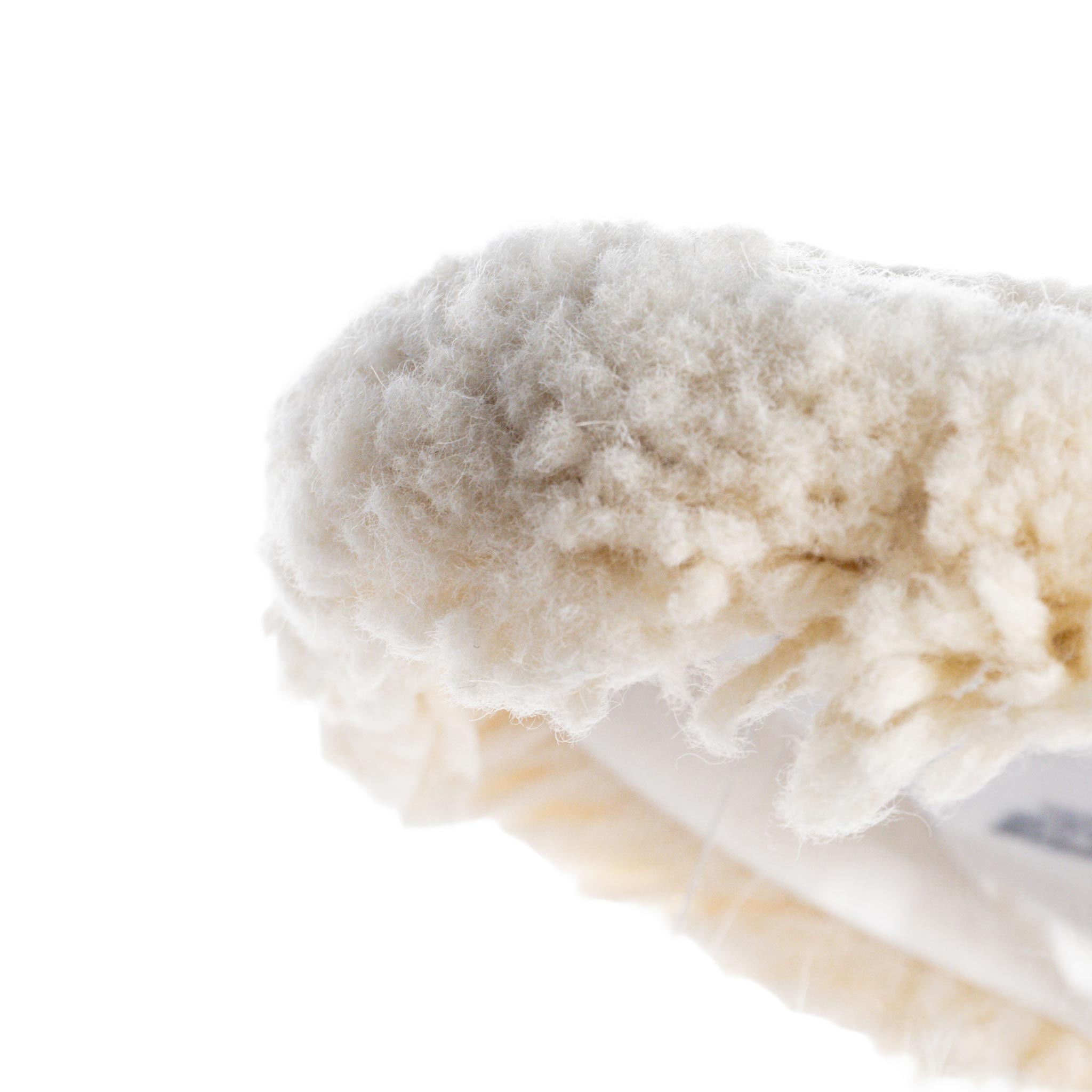Close-up of a fluffy white sheeps wool pad on a white background