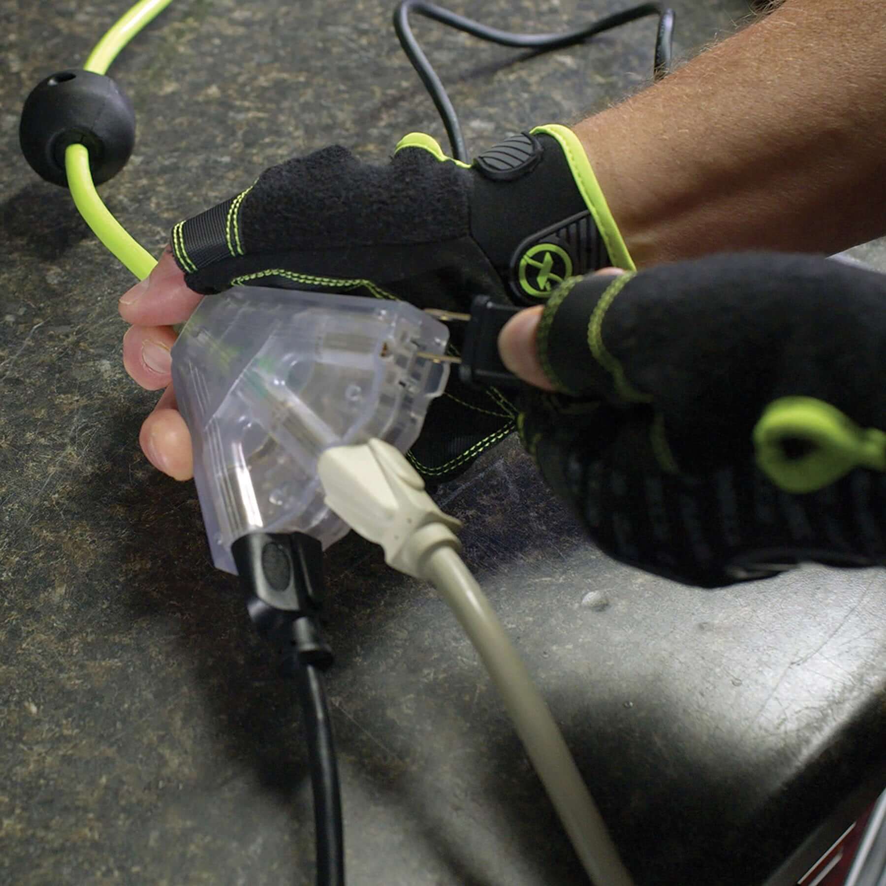 Person wearing gloves holding a flexzilla extension cord on a dark surface