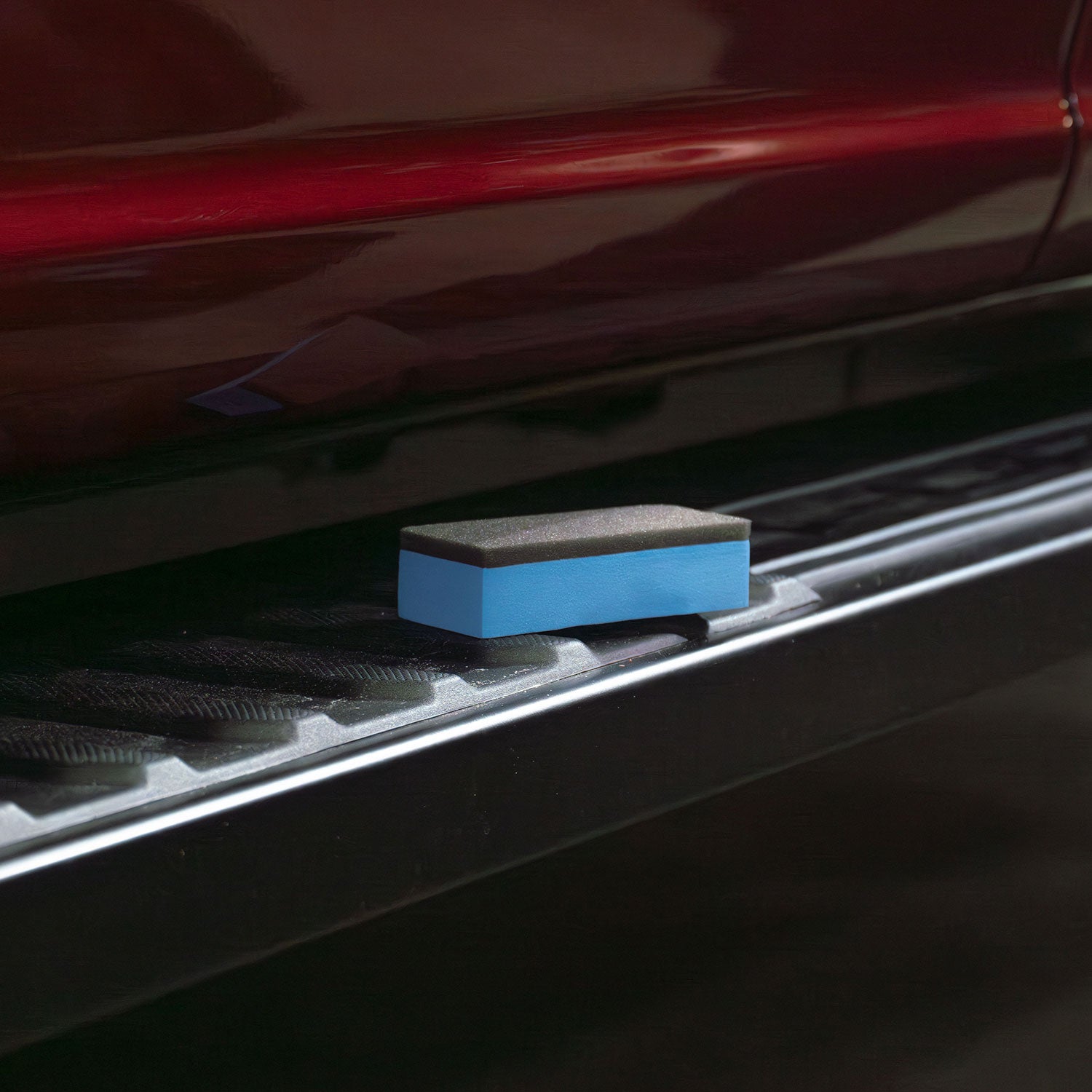 Blue coating applicator on a step bar for a red truck