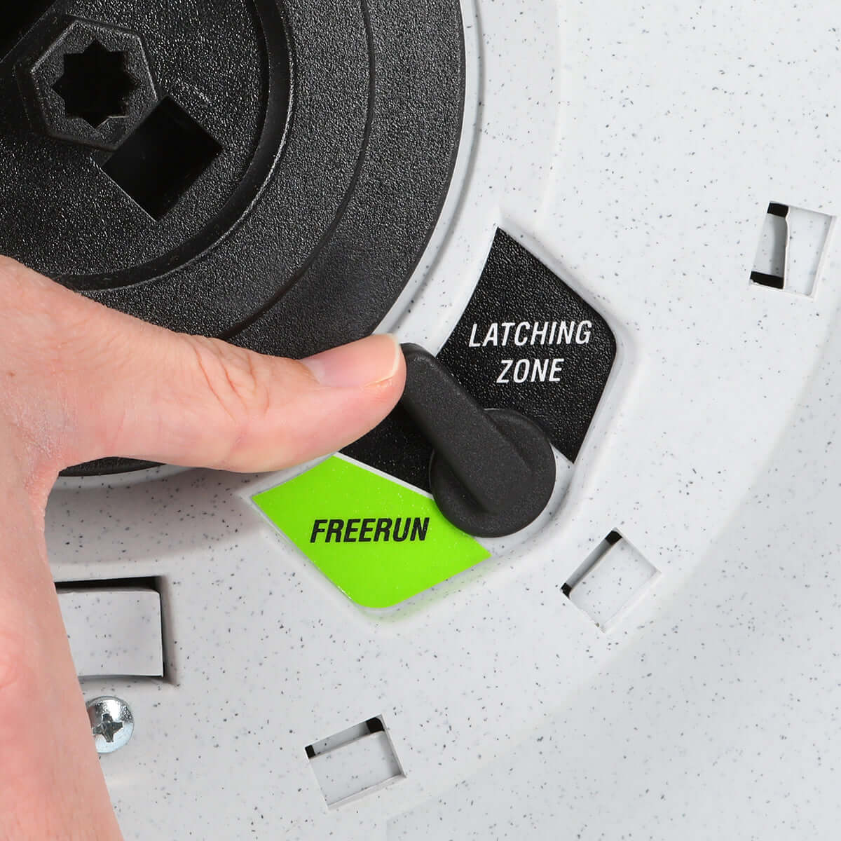 Hand interacting with a black component labeled 'Latching Zone' and 'Freerun' on a gray surface.