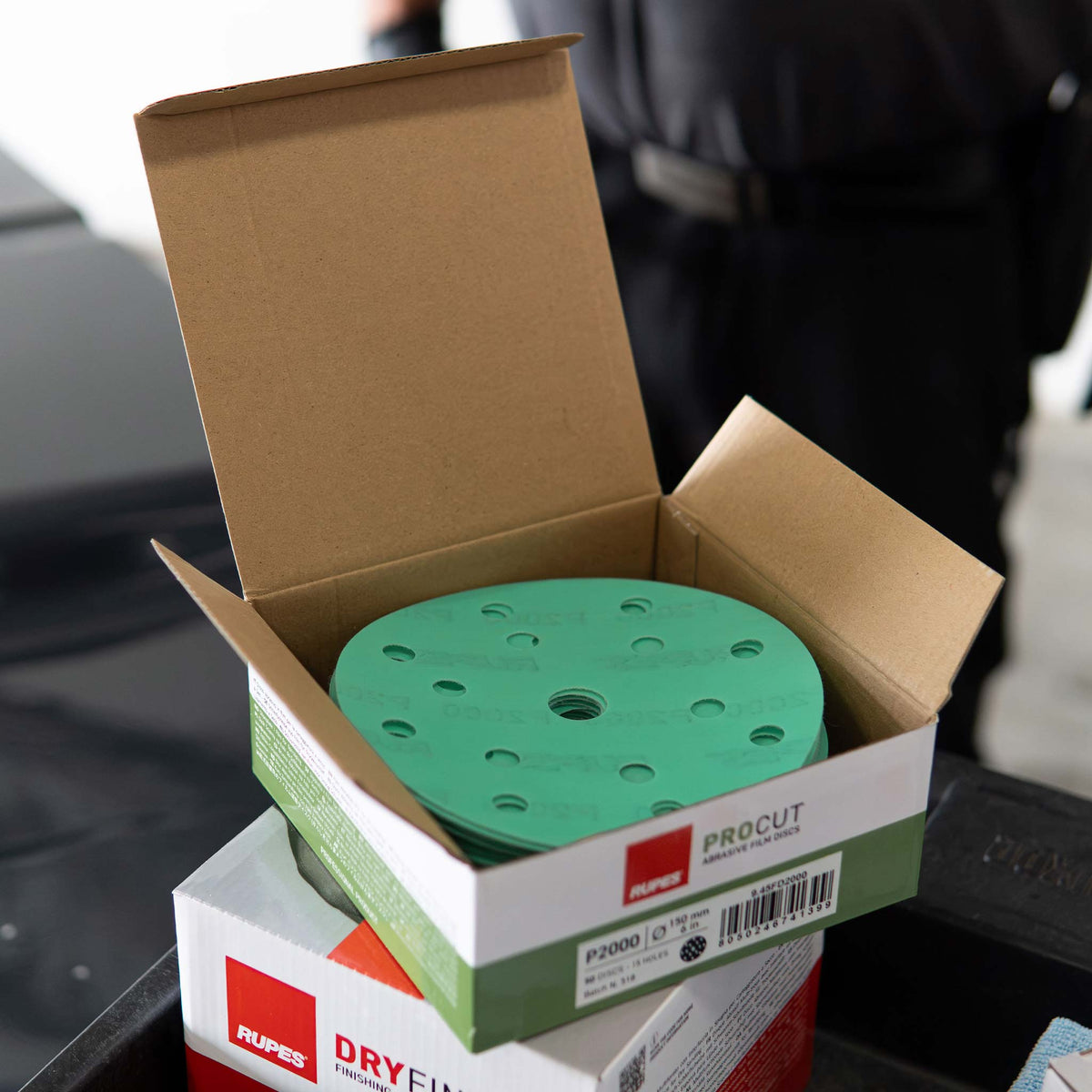Stack of green RUPES PROCUT P2000 discs in an open carton on a shop cart
