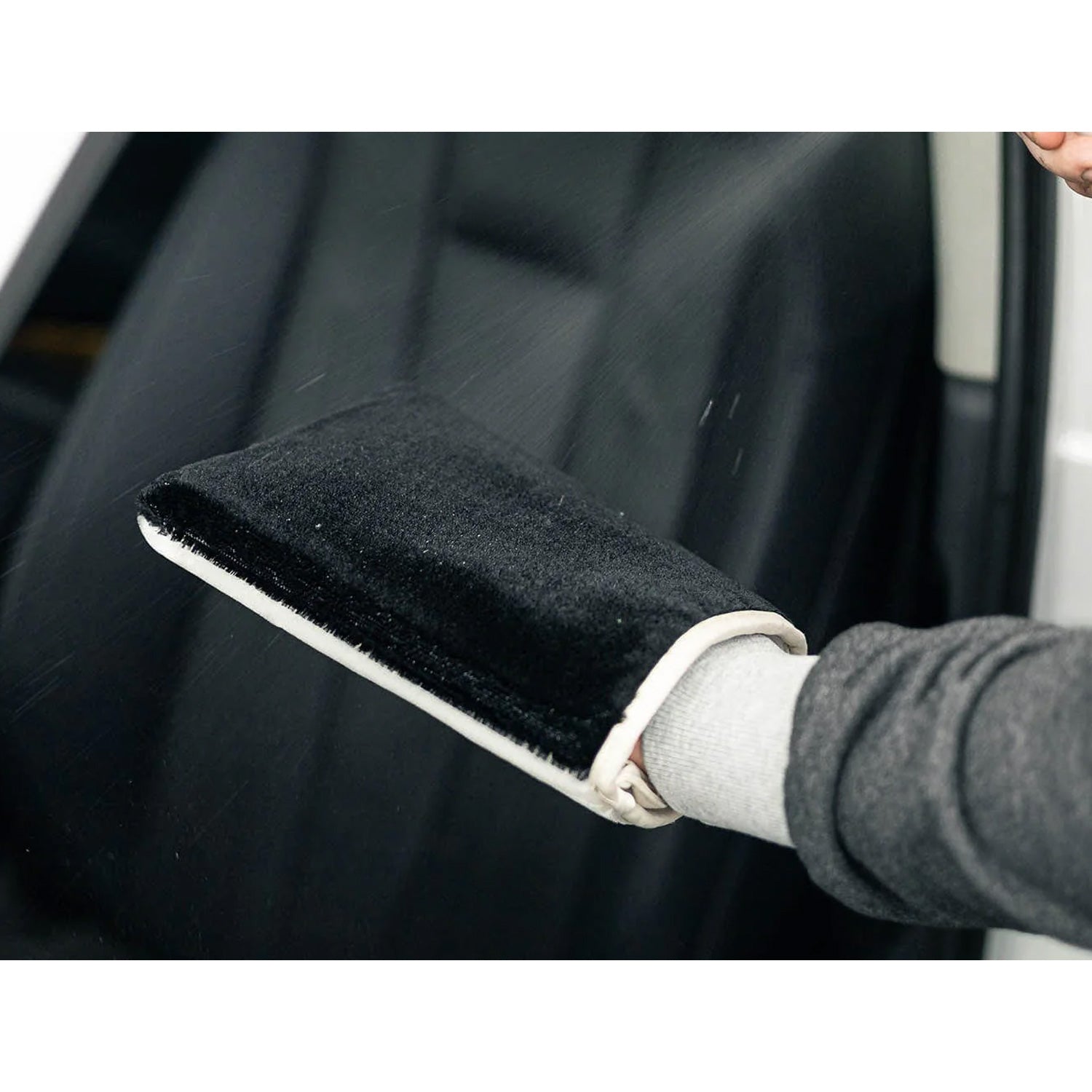 Person cleaning a car window with a white and black scrub ninja max