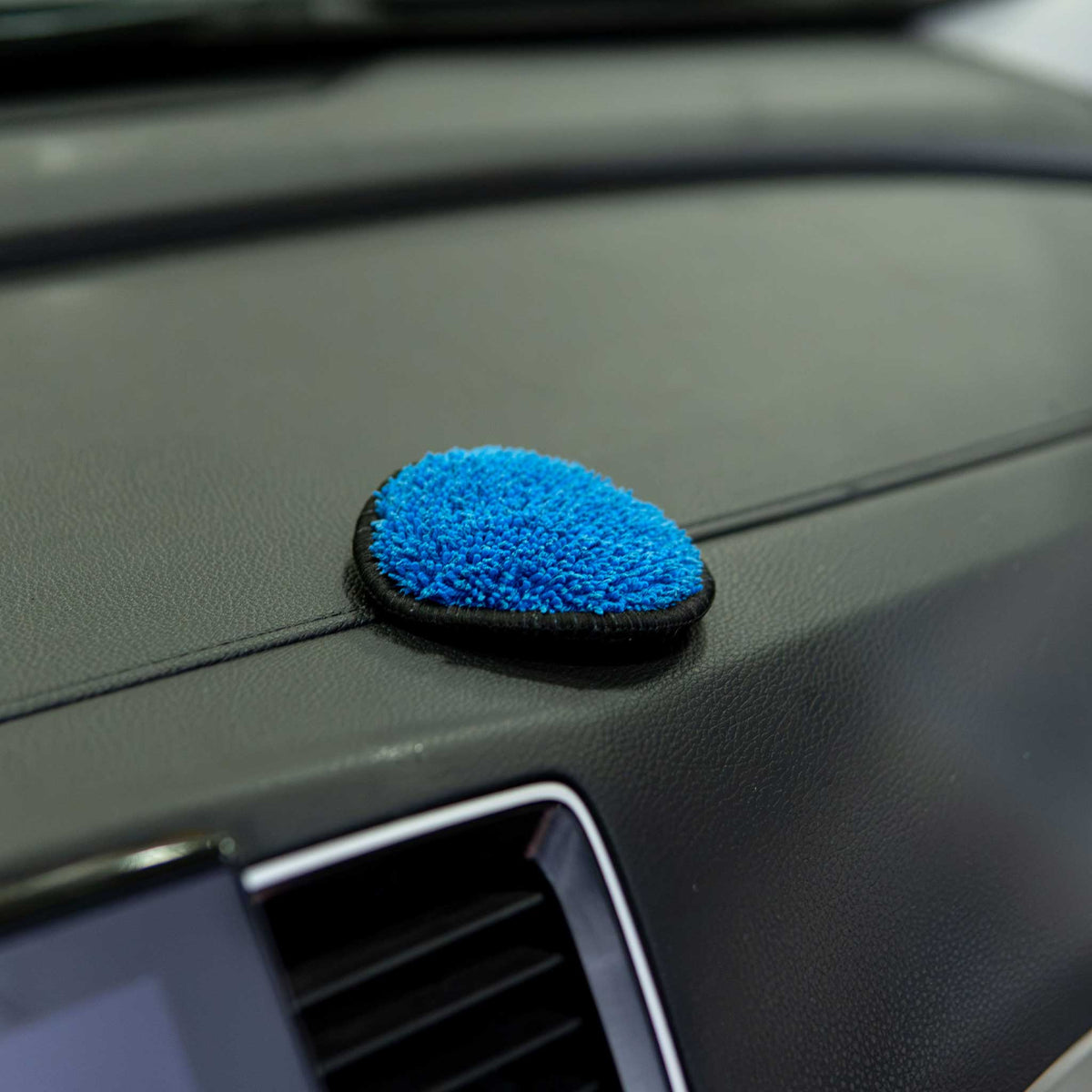 Autofiber UFO interior detailing pad sitting on a black car dashboard