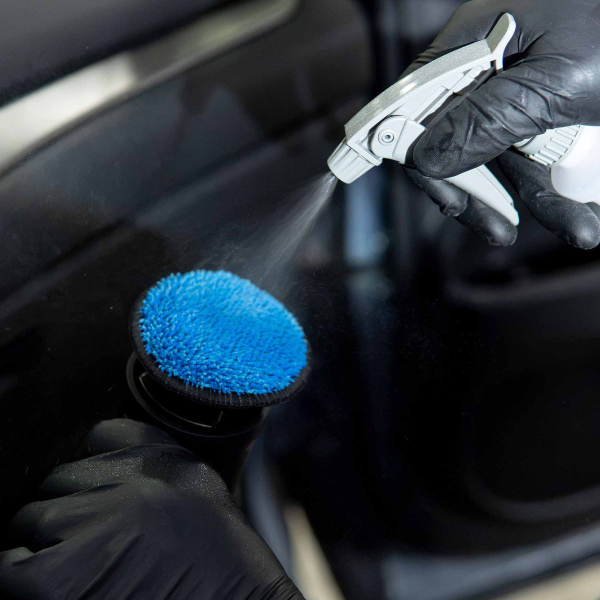 Autofiber UFO pad on a polisher while interior cleaner is sprayed onto the microfiber face