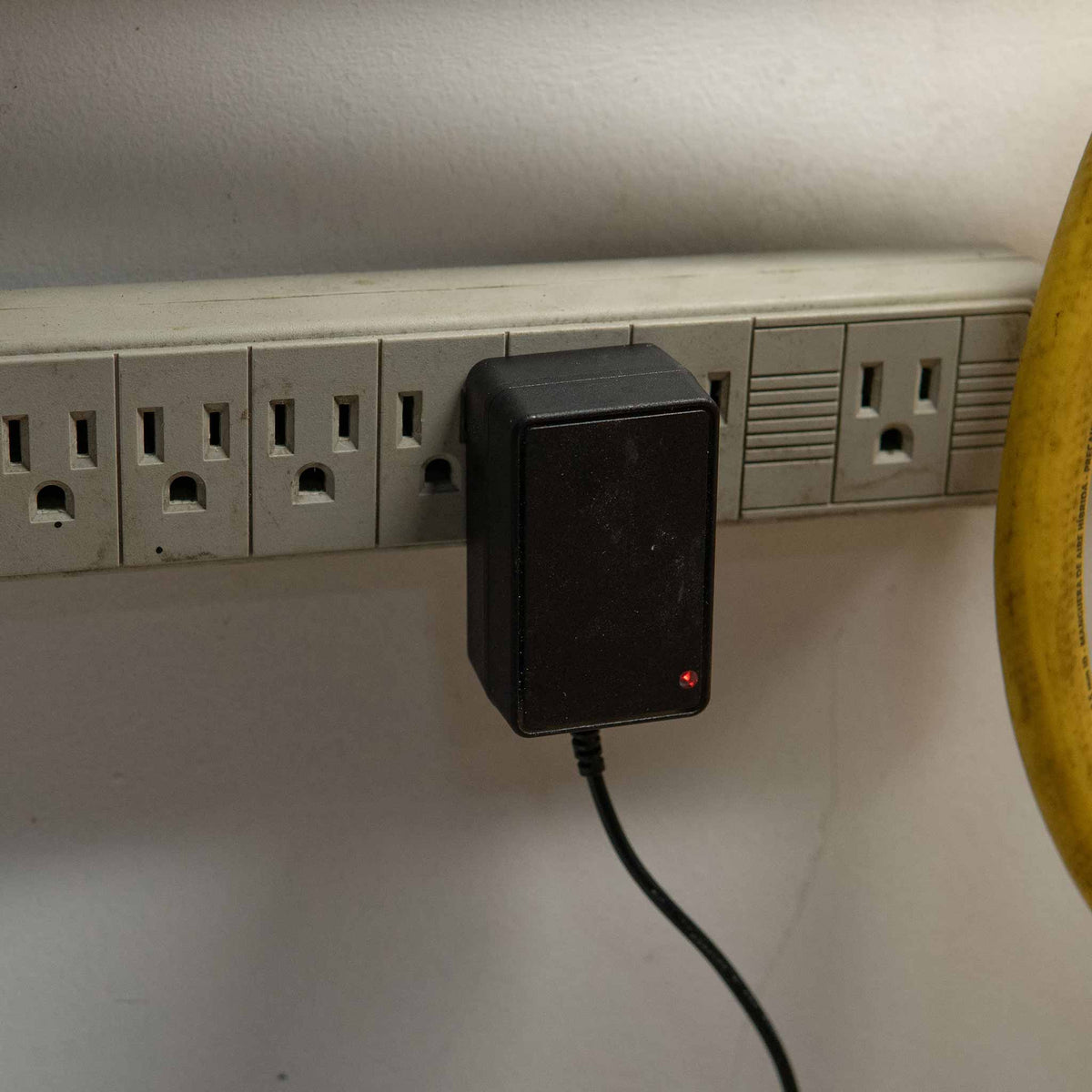 Barjack Raven charger plugged into a shop power strip with the red charging light on