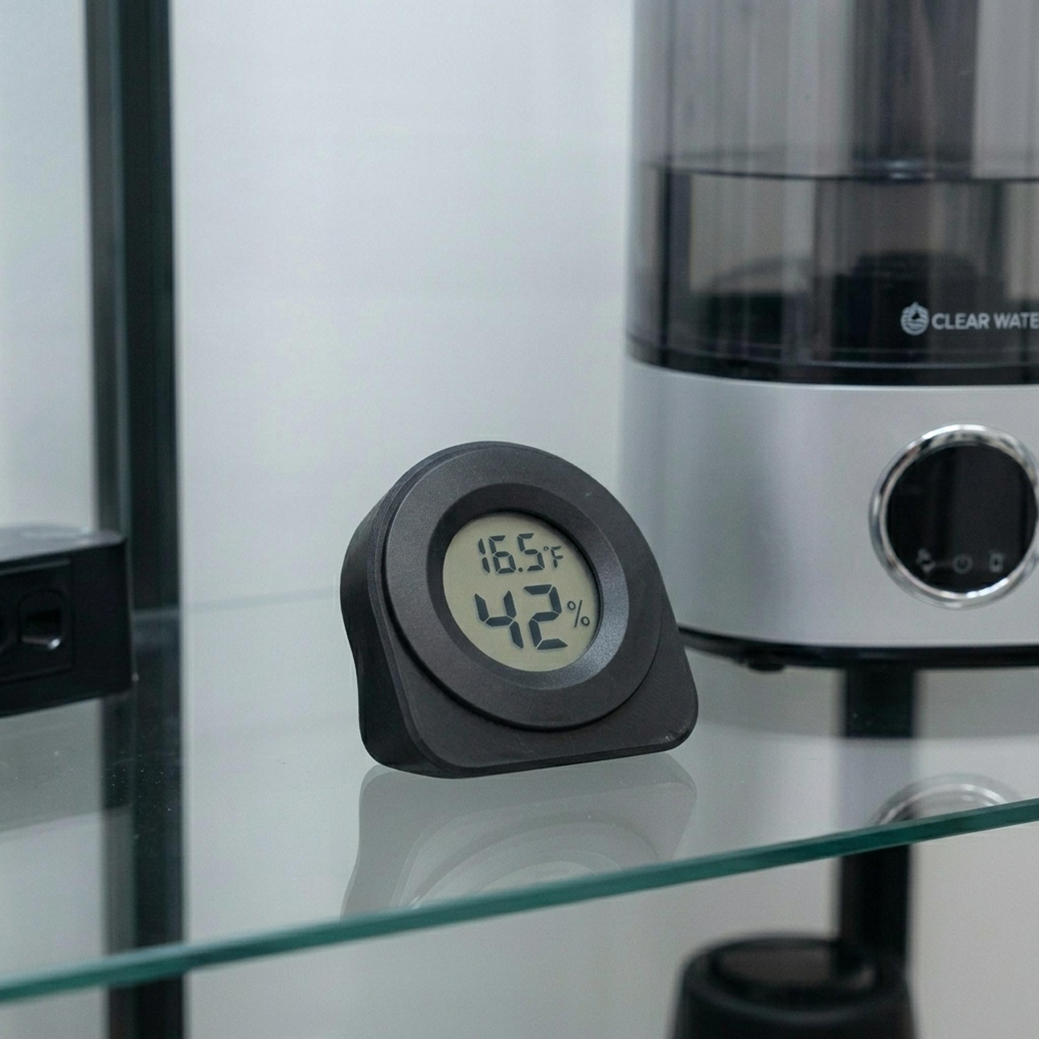 Black hygrometer in a kitchen setting reading temperature and humidity