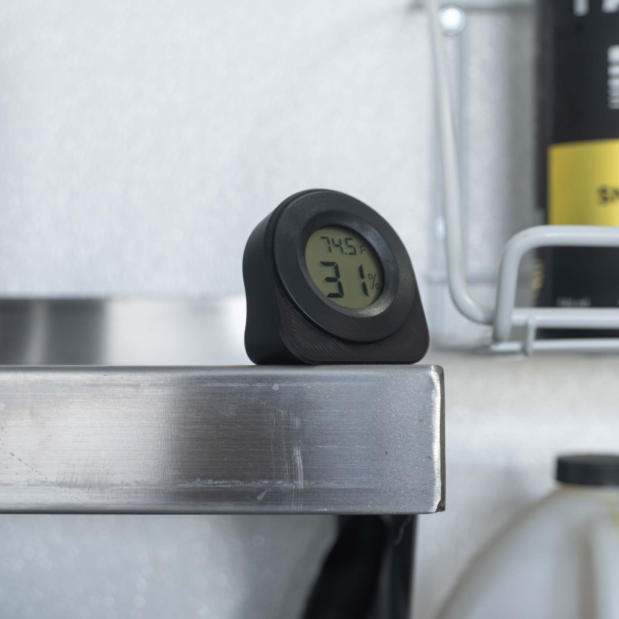Small black hygrometer in a shop setting reading temperature and humidity