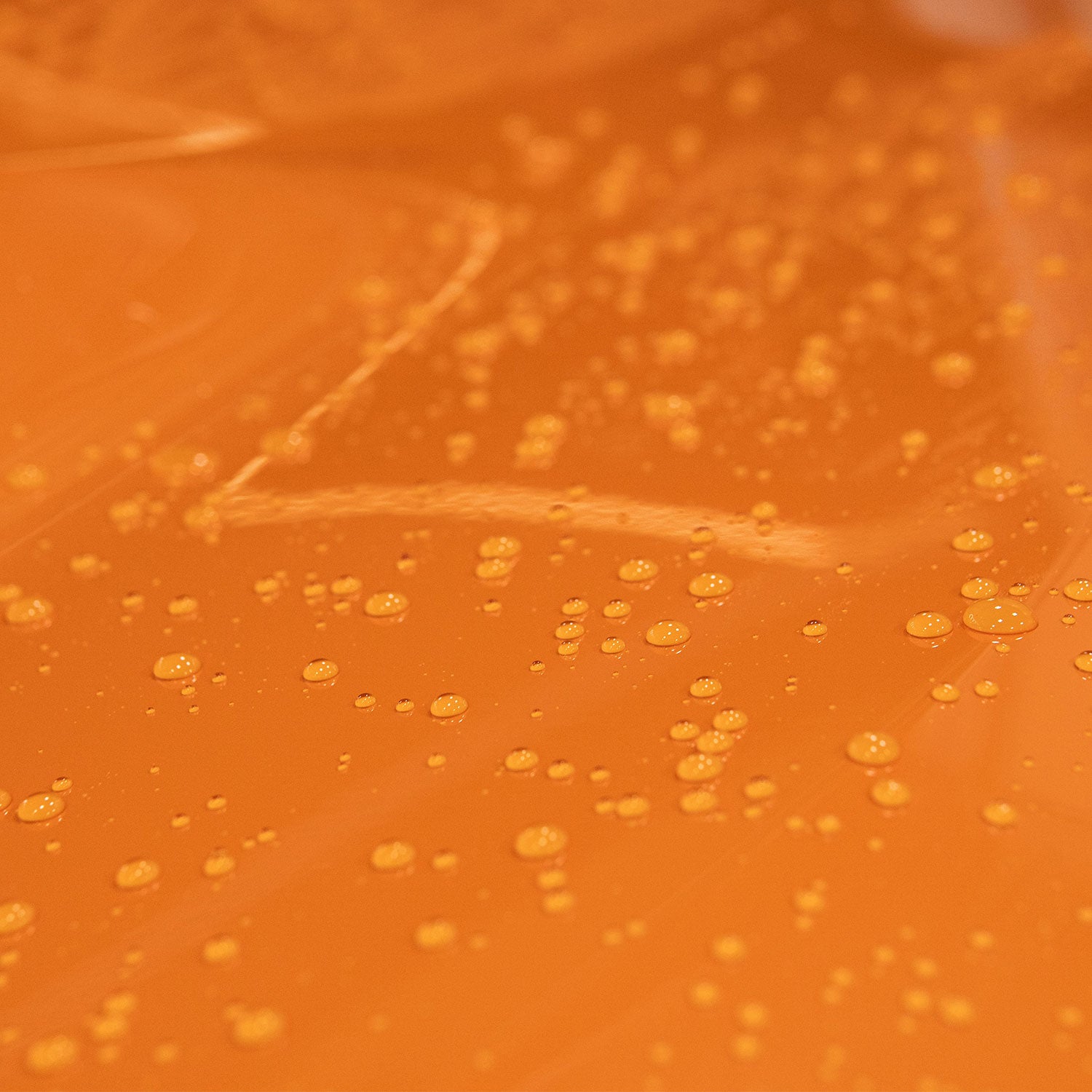 Close-up of water droplets on a textured orange surface