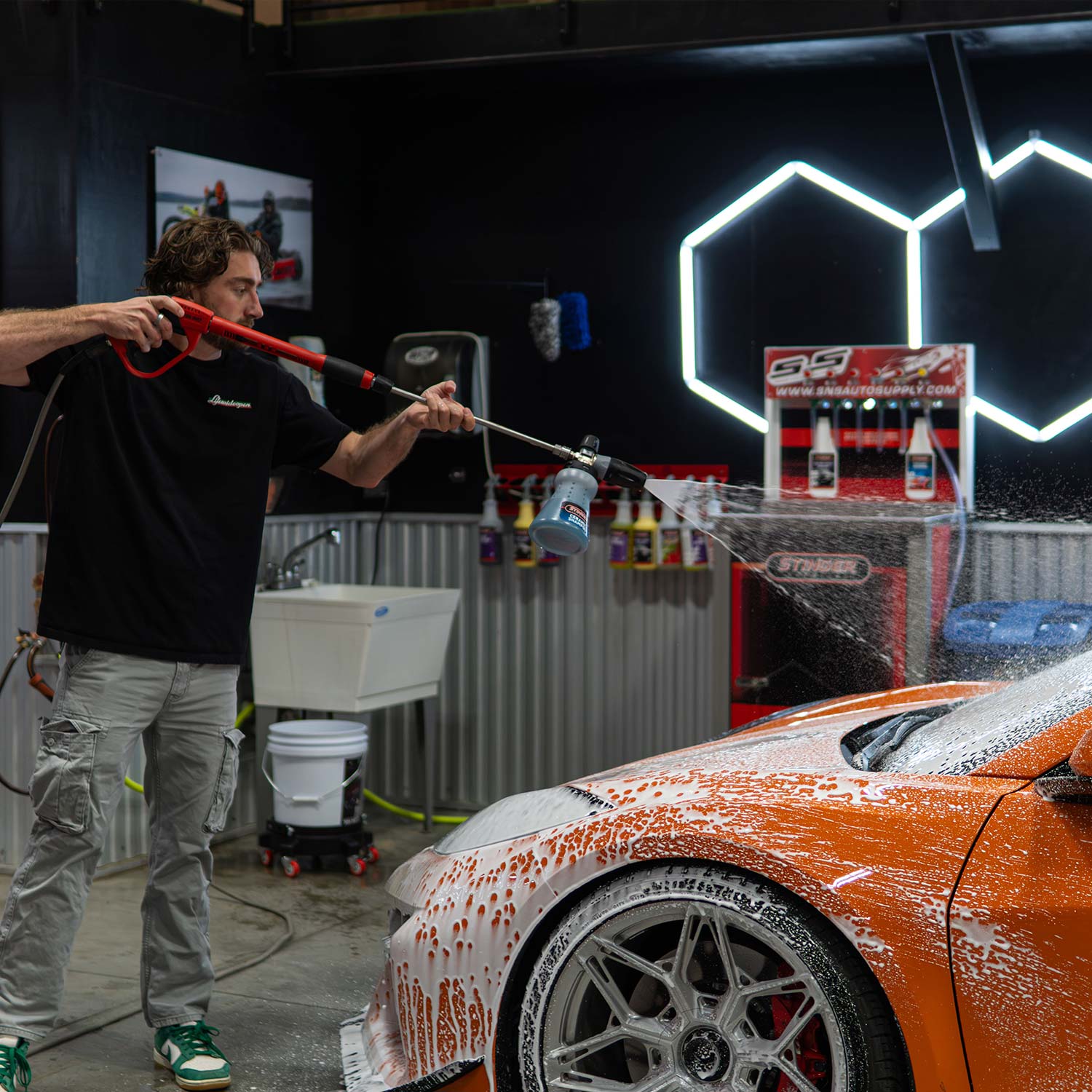 Ryan from CboysTV washing an orange corvette Z06 with ceramic soap in a garage setting