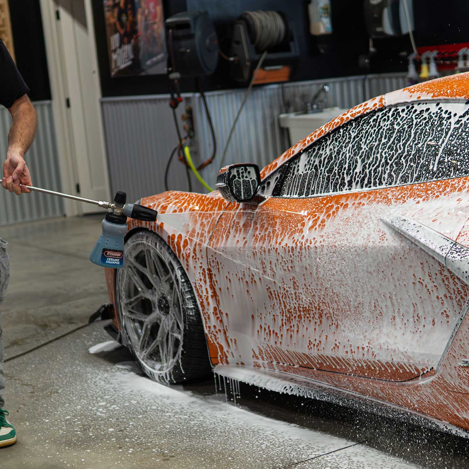 Ryan from CboysTV washing the side panel of an orange corvette Z06 with ceramic soap in a garage setting