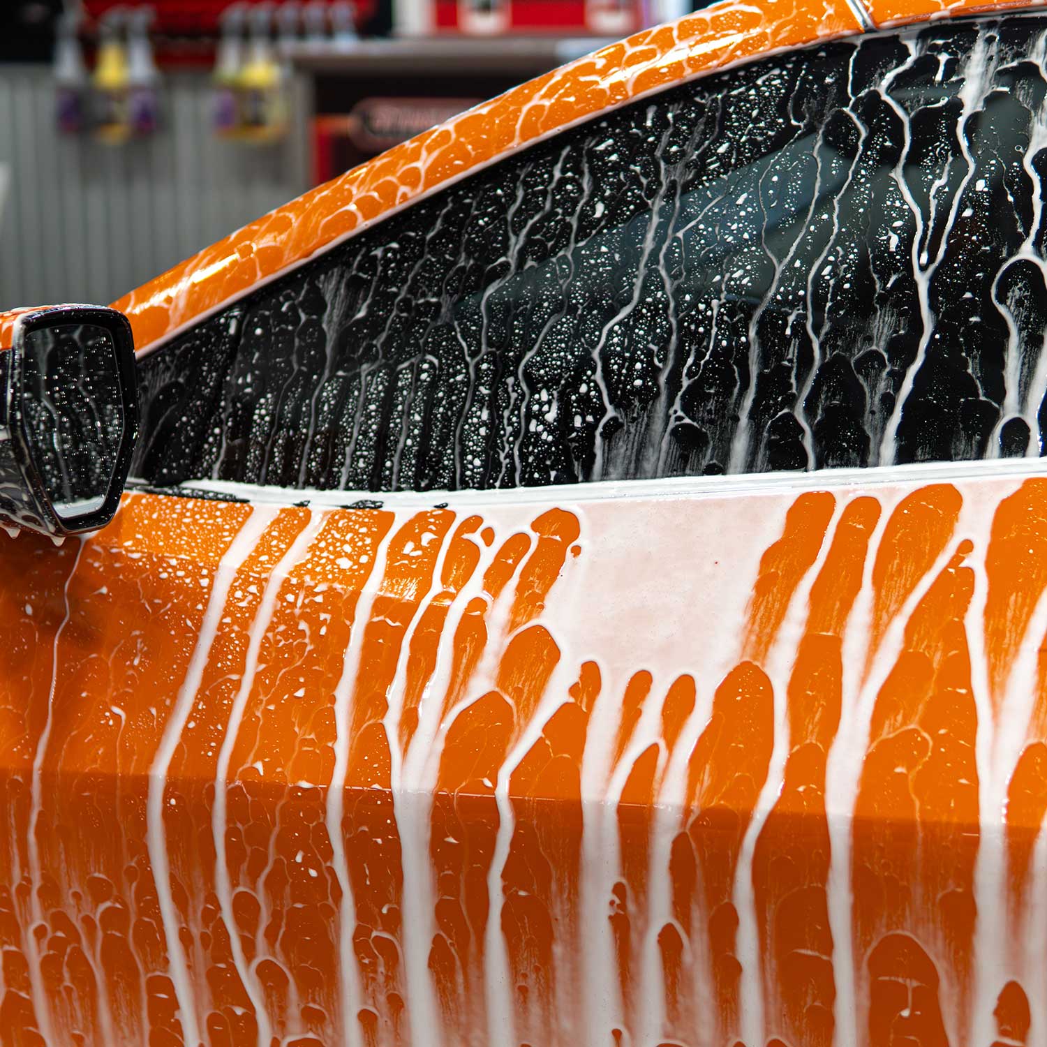 Close-up of a car's wet surface with ceramic soap suds, likely after a wash.