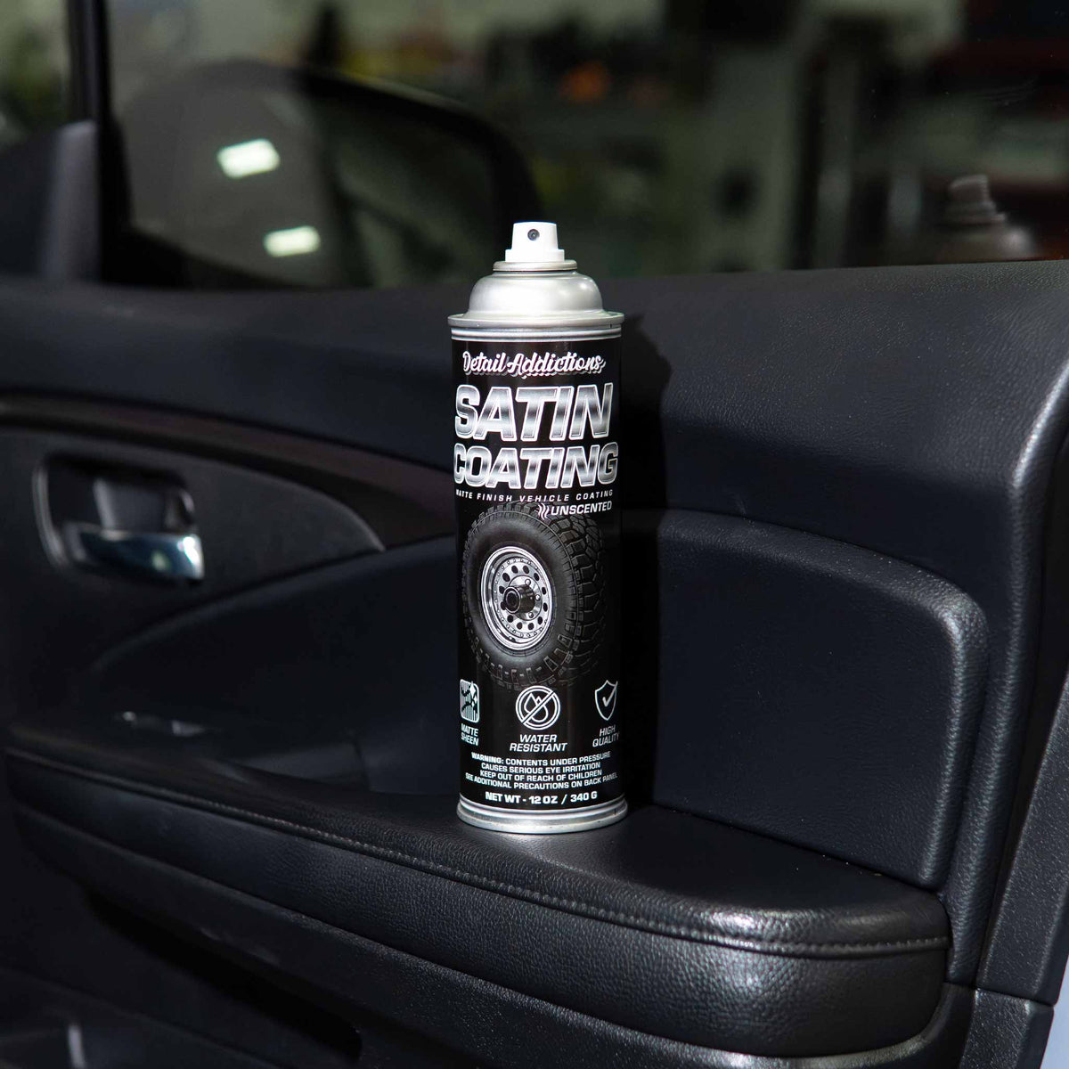 Detail Addictions Premium Satin Coating can standing on a black interior door panel in a shop