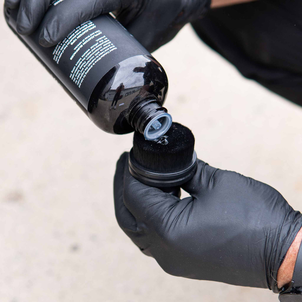 Pouring tire dressing straight onto the dense nylon bristles of the Detail Addictions brush