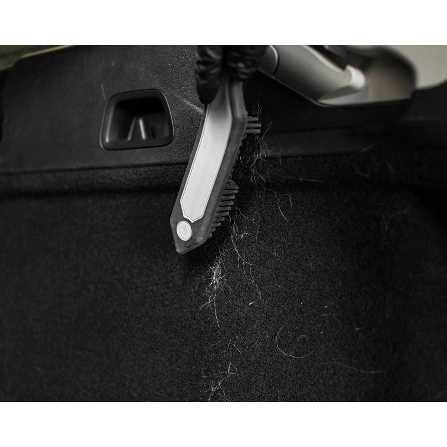 Car interior cleaning brush removing pet hair from a car seat.