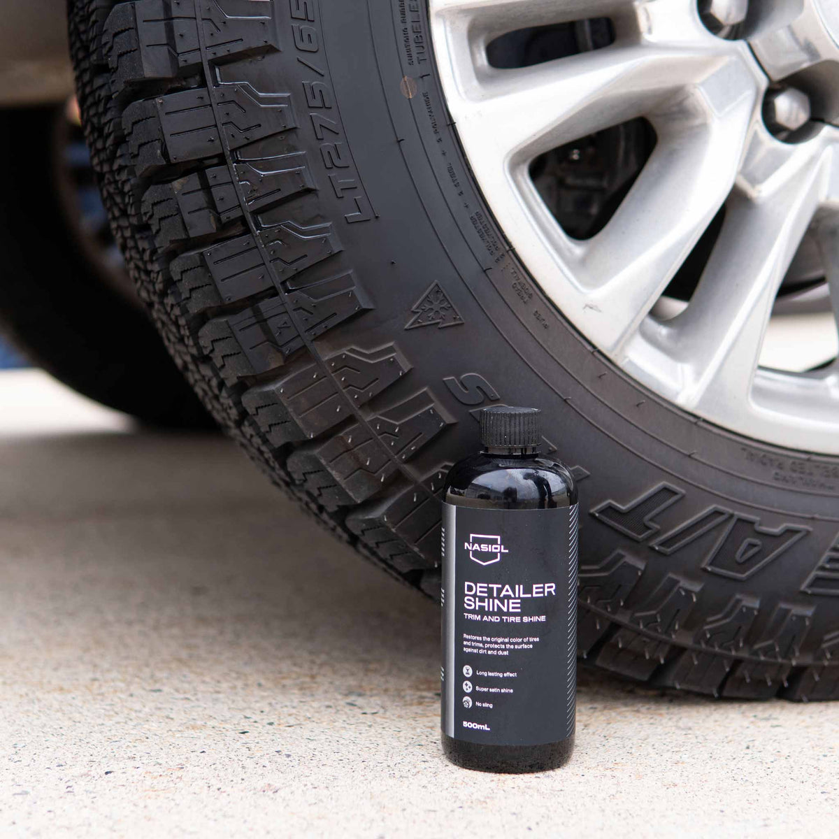 Nasiol Detailer Shine 500 mL bottle in front of a dressed all-terrain tire and alloy wheel