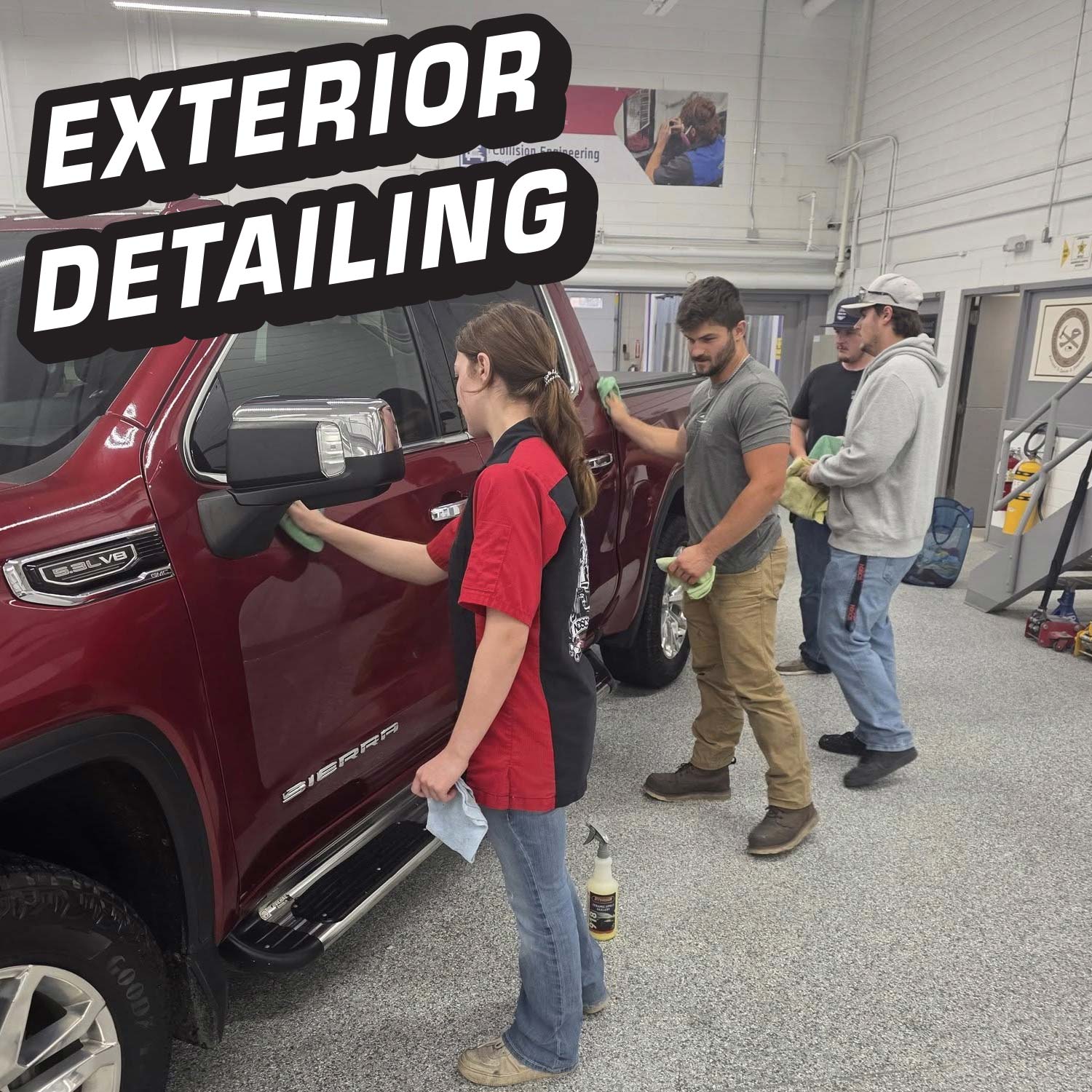 People working on exterior detailing of a red SUV in a garage.