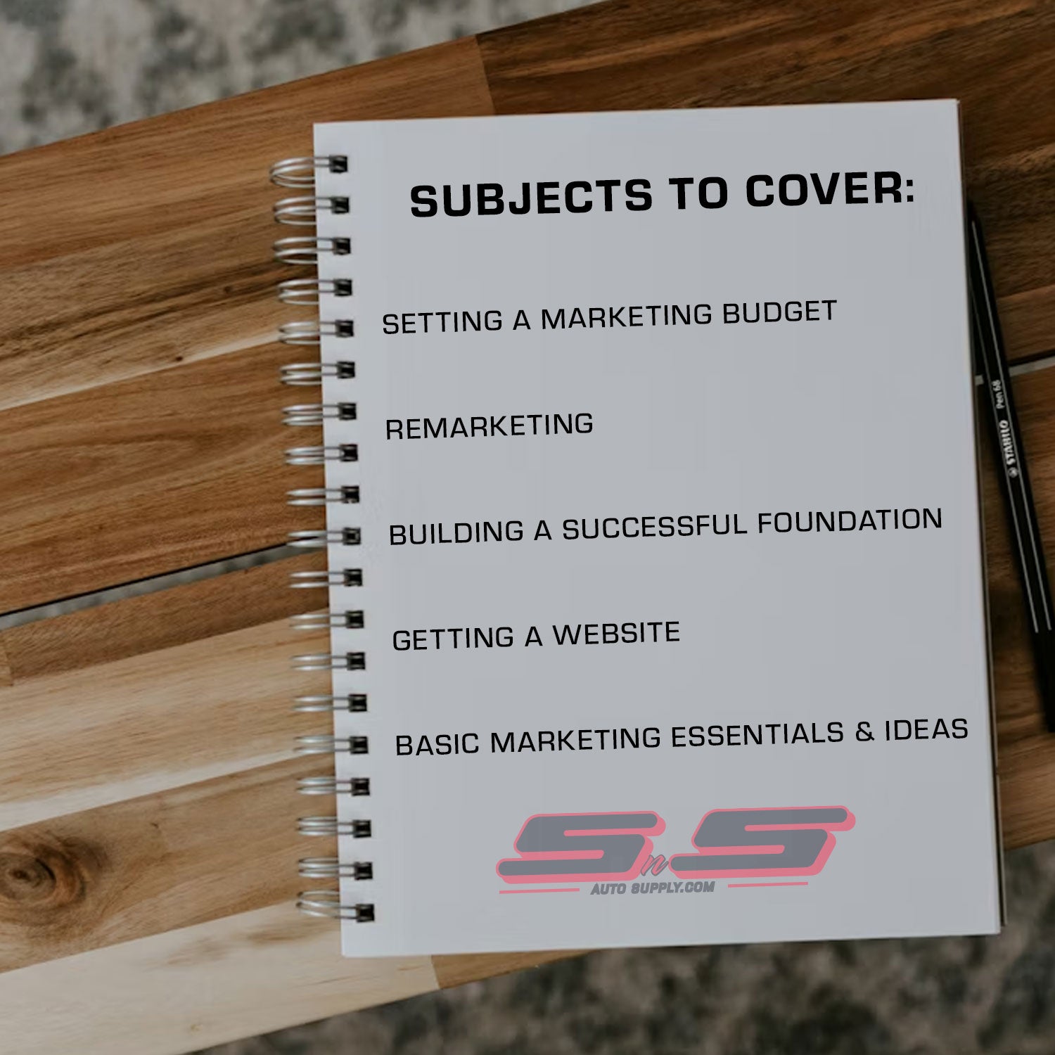 Notebook with marketing topics listed on a wooden surface