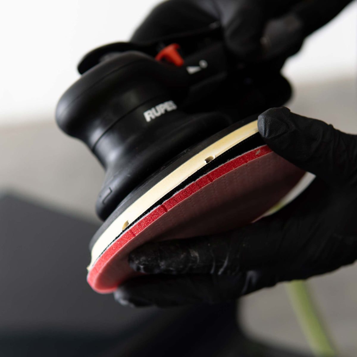 Pressing a RUPES DryFinish disc onto the hook and loop backing pad of a RUPES sander