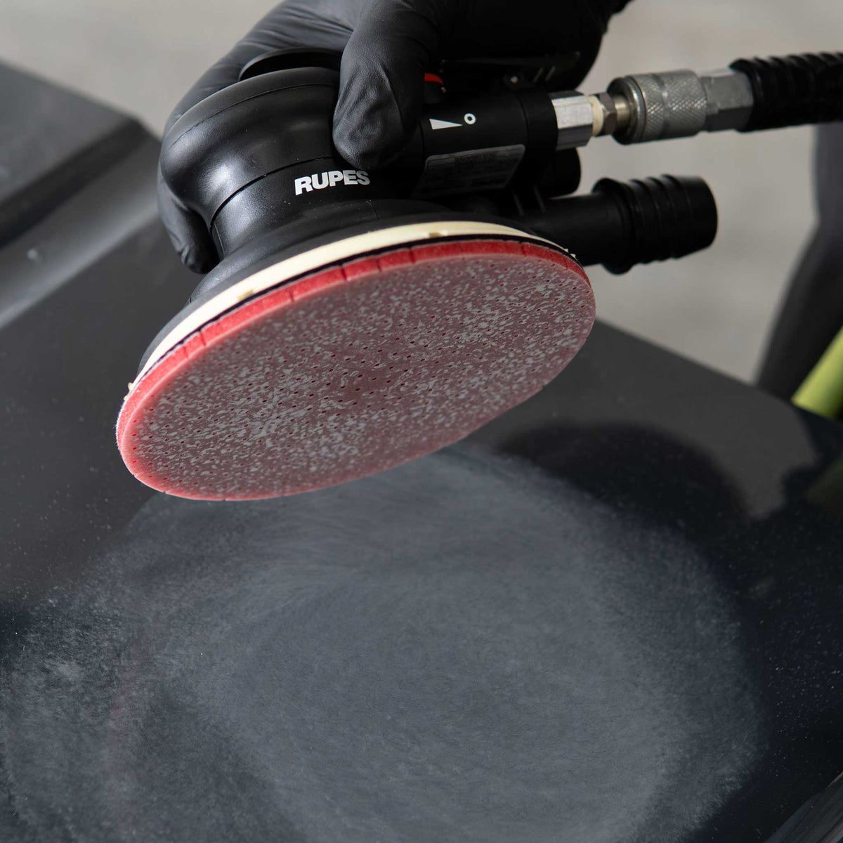 RUPES sander with a DryFinish disc lifted over a dry sanded black hood