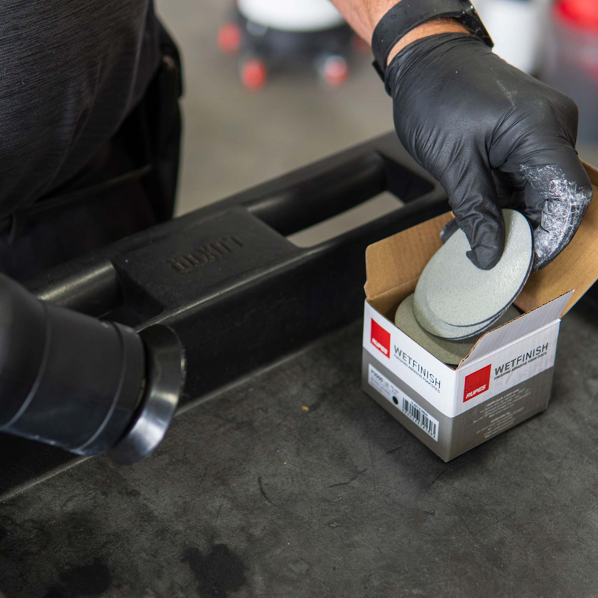 Pulling a 3 inch RUPES WetFinish P3000 disc from its box in a body shop