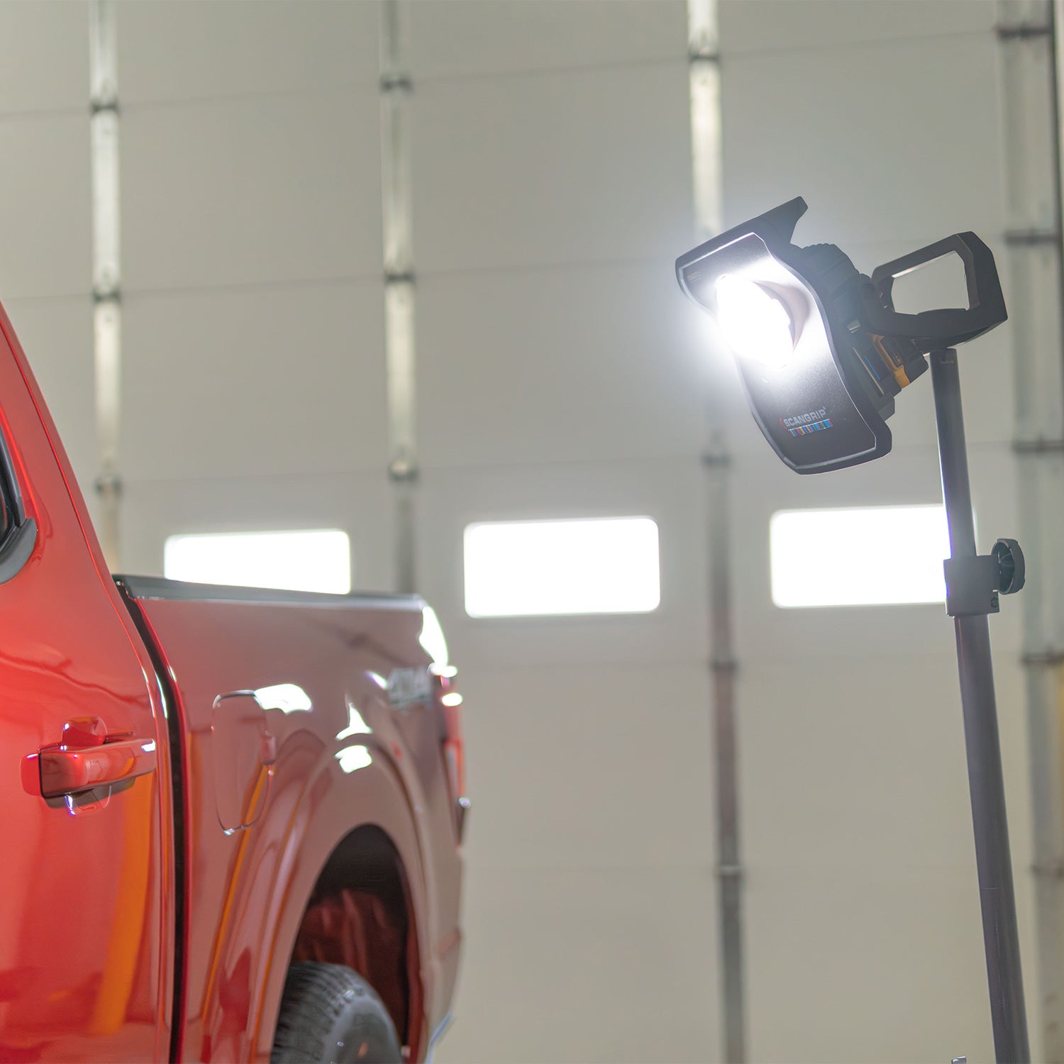 Red pickup truck with a portable work light in a garage setting