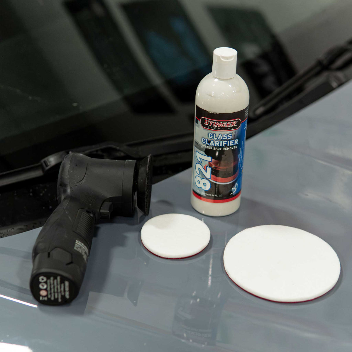 Stinger 821 Glass Clarifier, a 3 inch polisher, and rayon glass pads set up on a car hood