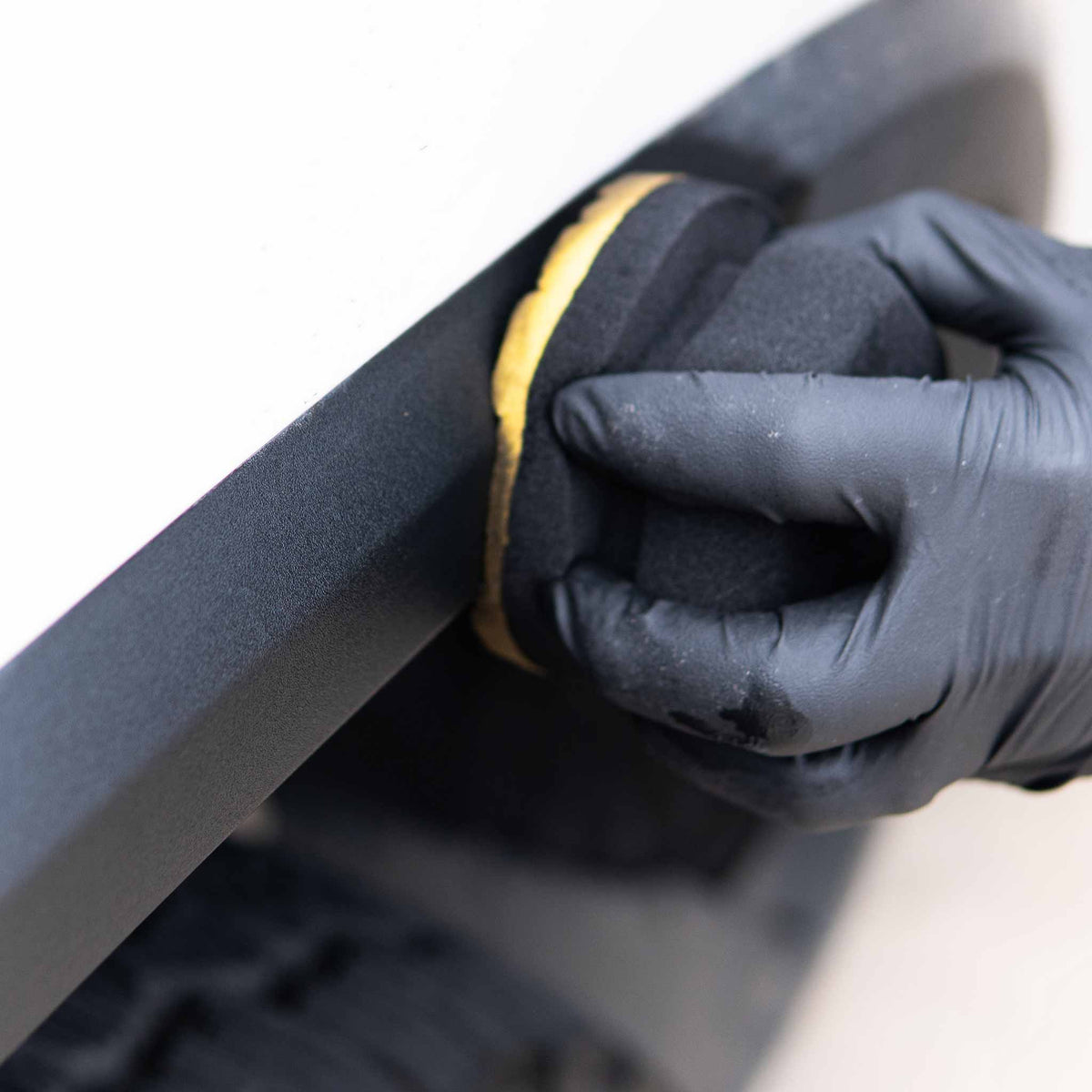 Dressing a black textured fender flare with the Stinger hex pad applicator on a white vehicle