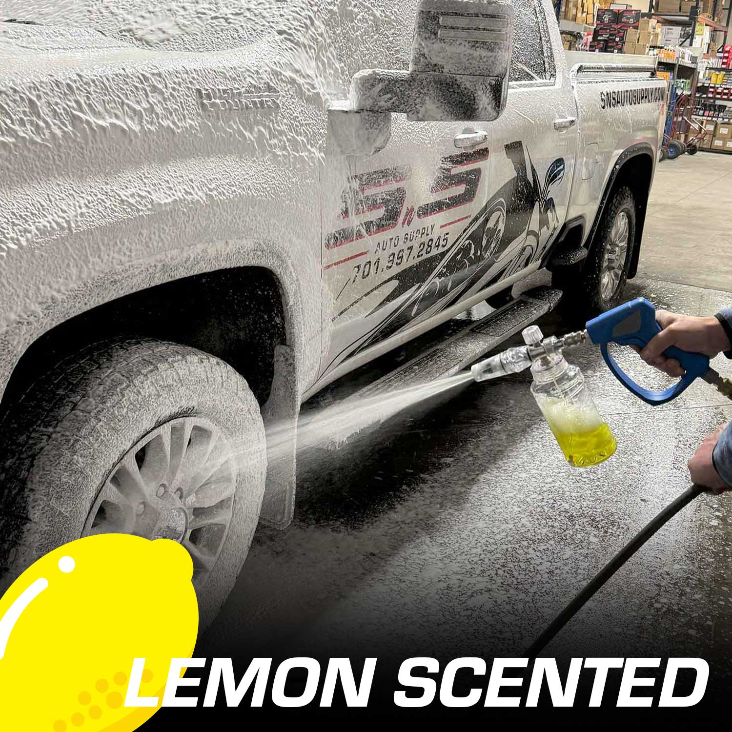 Person washing a white truck with a lemon-scented soap in a foam cannon.