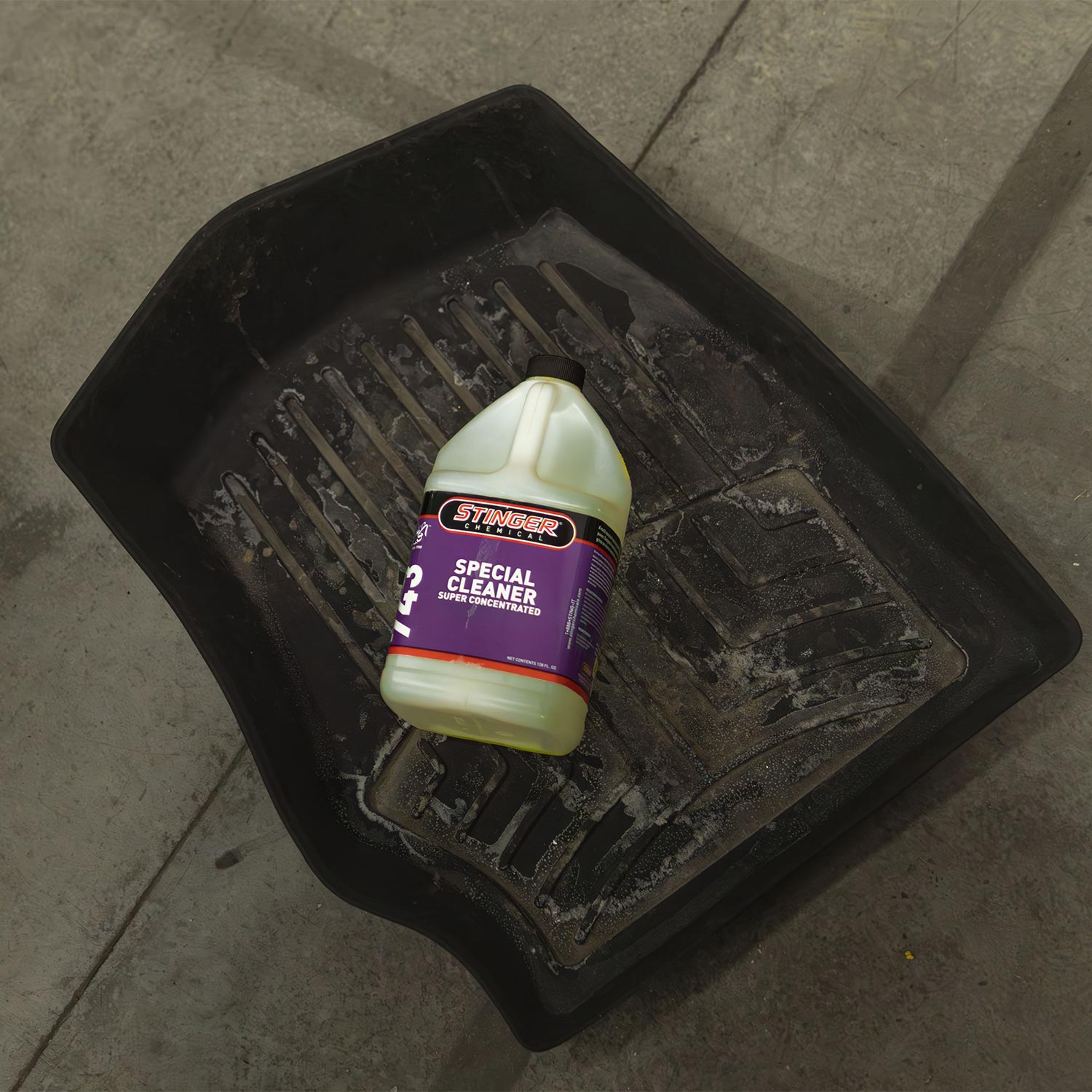 Bottle of Stinger Special Cleaner on a black floor mat with a concrete floor background
