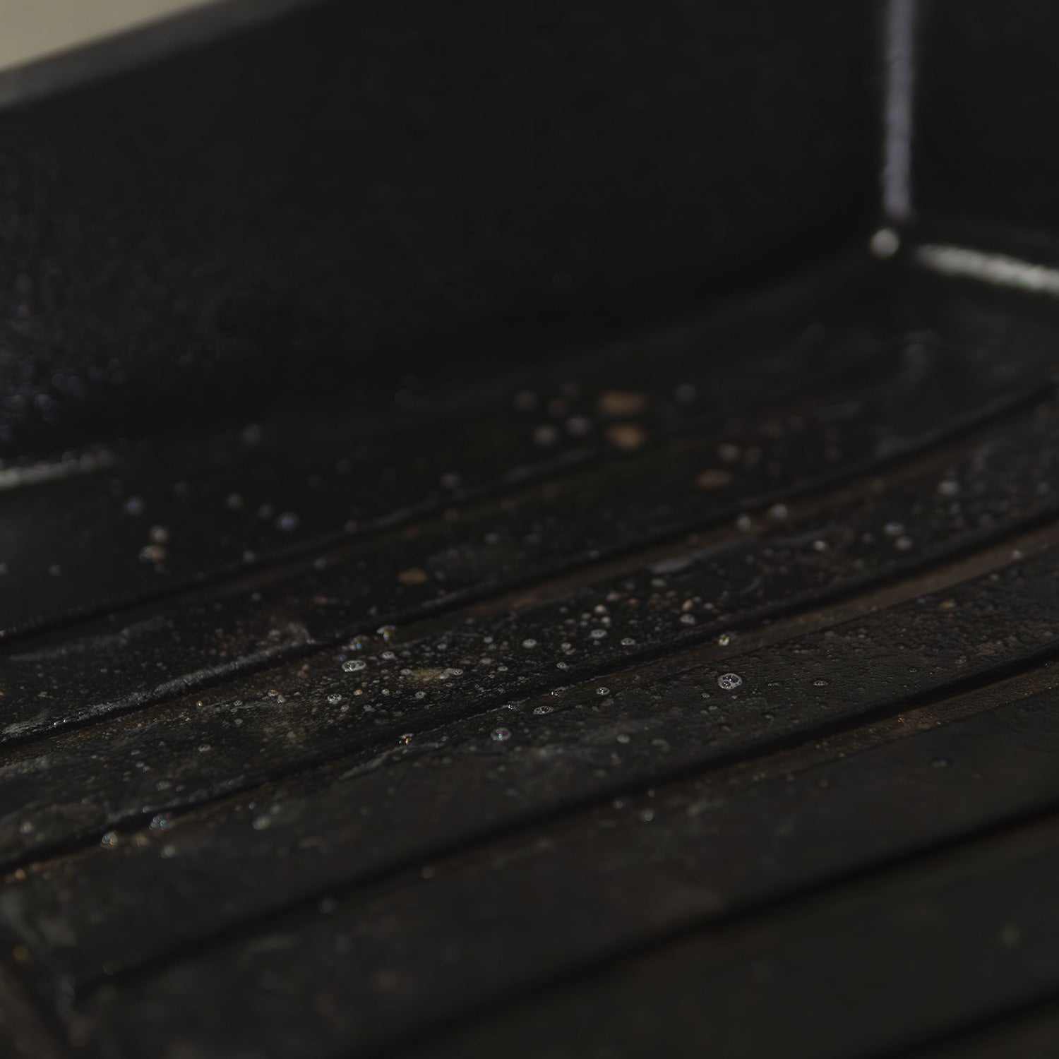 Close-up of a dark, textured floor mat with visible cleaner on it