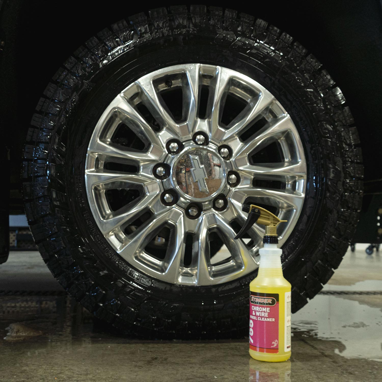 Car wheel with a bottle of Stinger Chemical's wheel cleaner on a wet surface