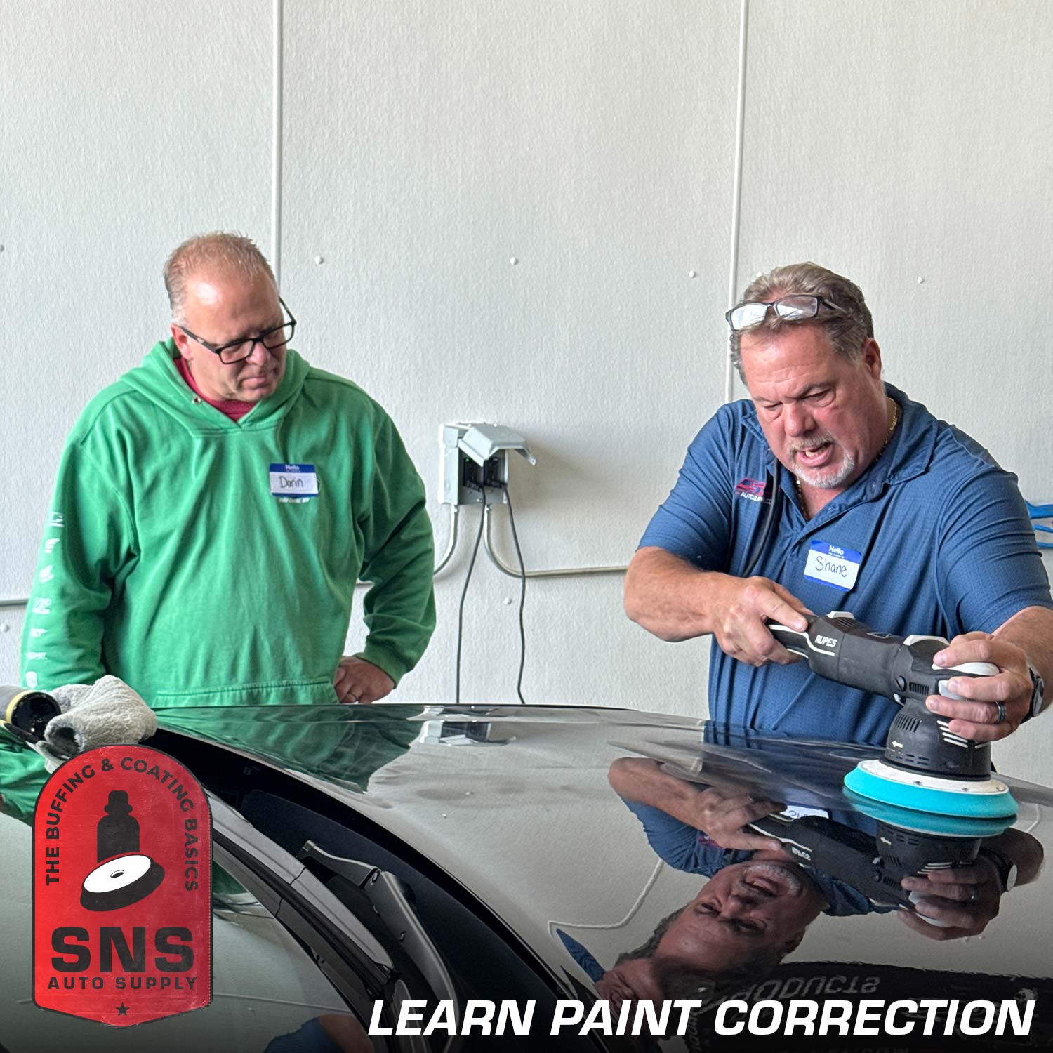 Two men working on a car with SNS Auto Supply logo, learning paint correction.