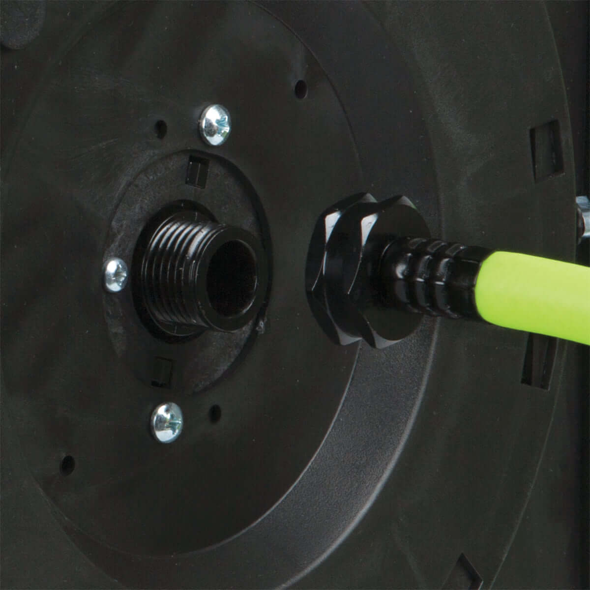 Close-up of a black mechanical component with a flexzilla hose and screws.