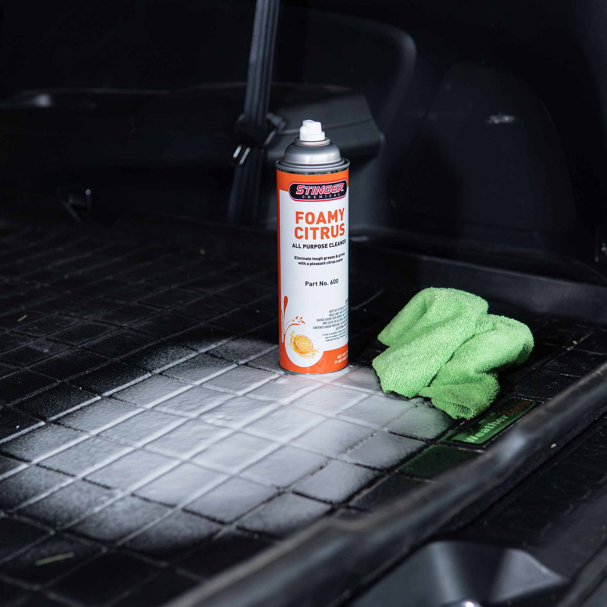 Stinger Chemical Foamy Citrus 600 can on a foam-covered rubber floor mat beside a green microfiber towel