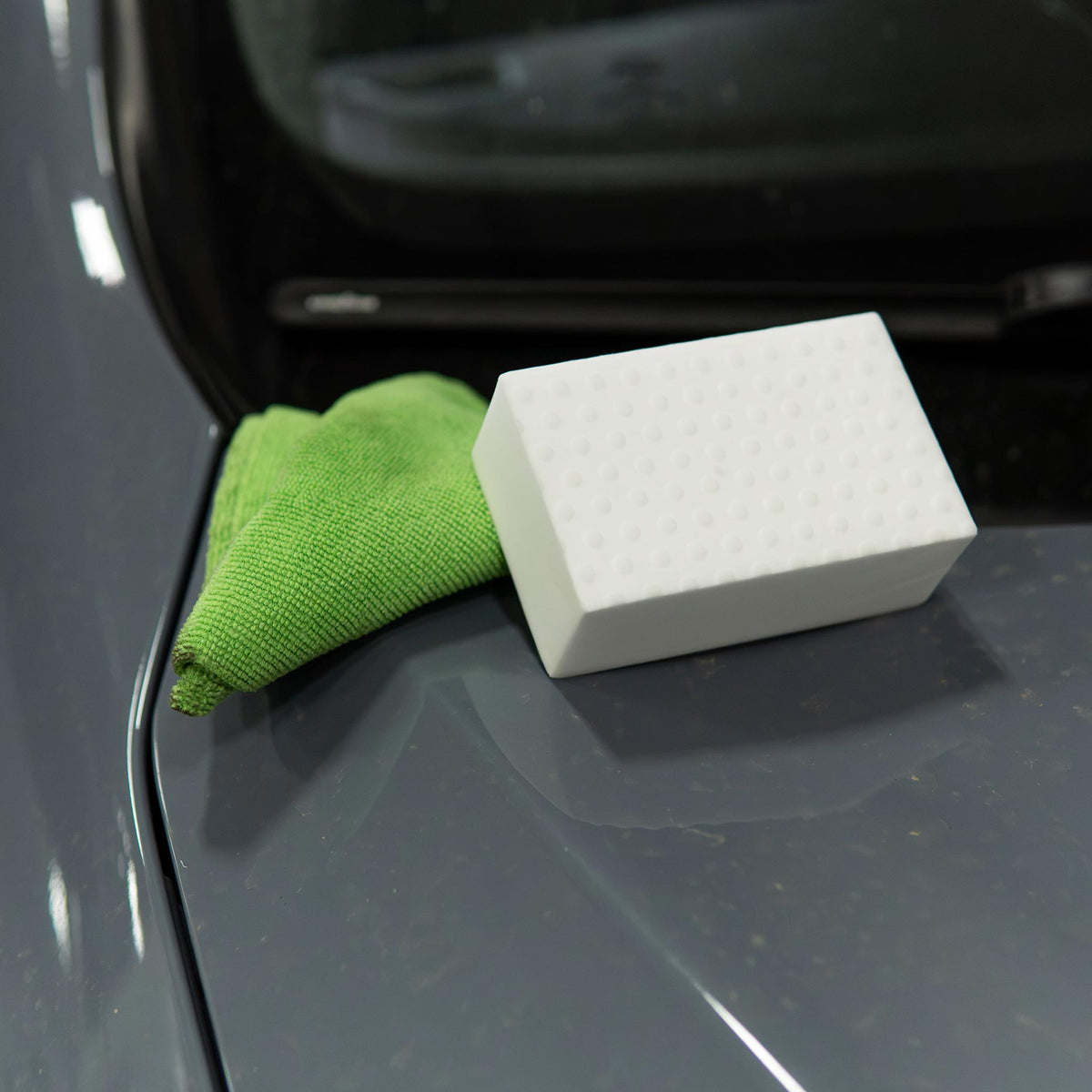 Stinger Chemical Heavy Duty Magic Nano Sponge and a green microfiber towel resting on a car hood