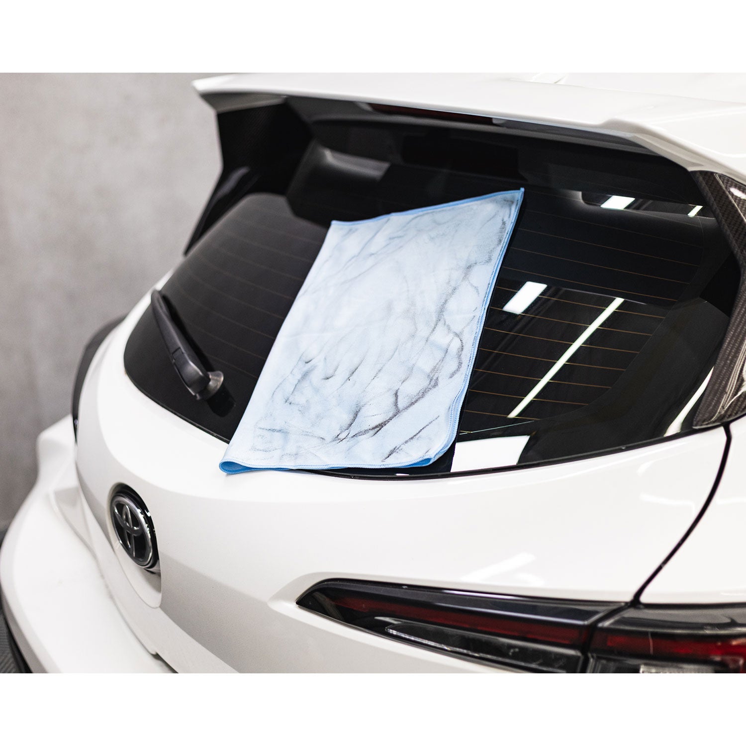 Rear Car hood with a dirty blue microfiber towel on a white background