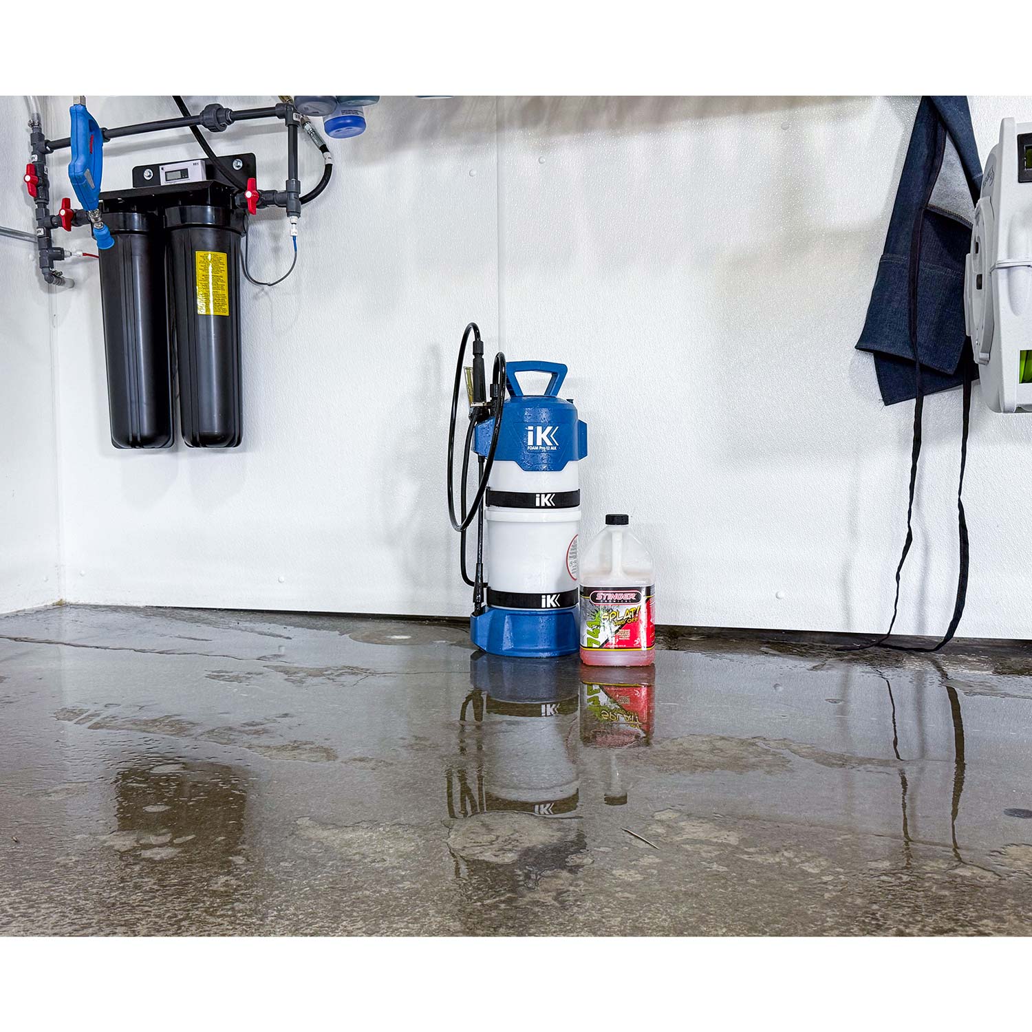 IK and Stinger Cleaning equipment and supplies on a concrete floor with a white wall in the background.
