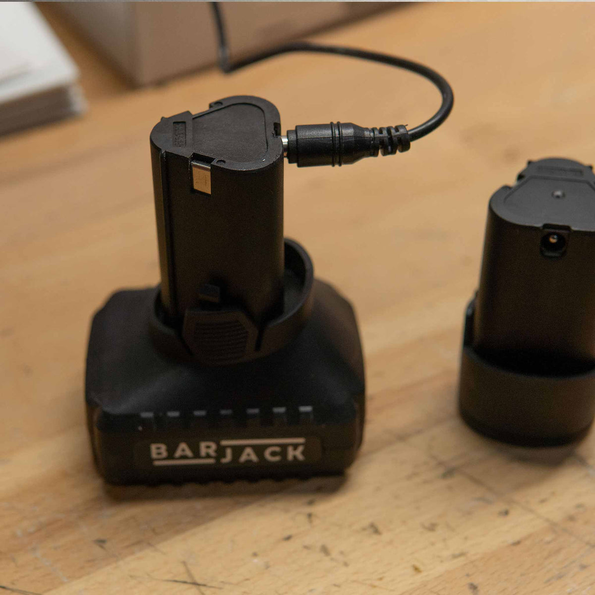 Barjack Raven 5Ah standing battery charging next to a 2.5Ah pack on the bench