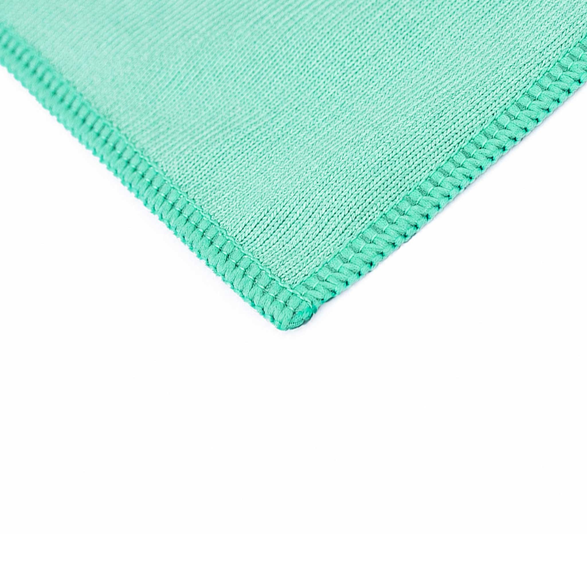 Close-up of a textured green towel corner on a white background