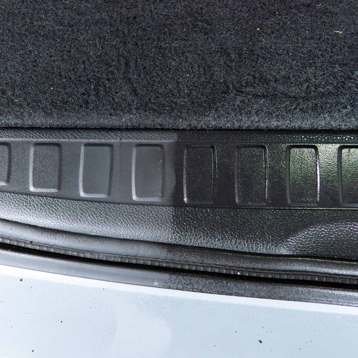 Detail Addictions Premium Gloss Dressing before and after on faded black plastic trunk trim