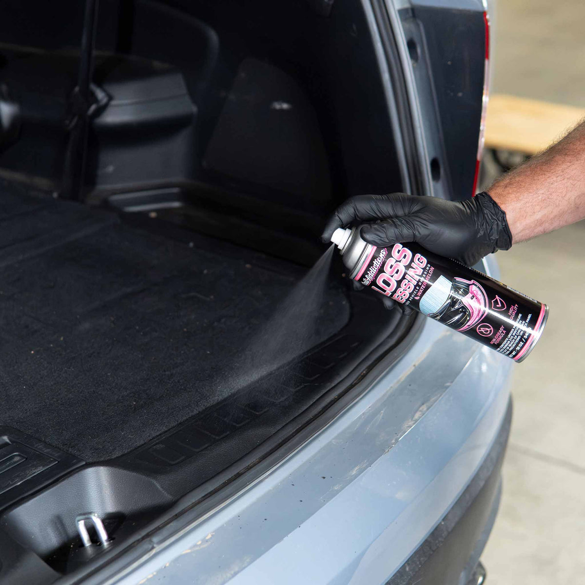 Detail Addictions Premium Gloss Dressing sprayed on black plastic cargo sill trim in an SUV