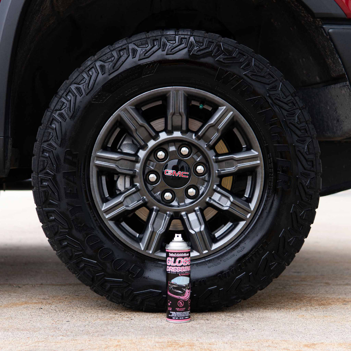Detail Addictions Premium Gloss Dressing aerosol in front of a glossy all-terrain truck tire