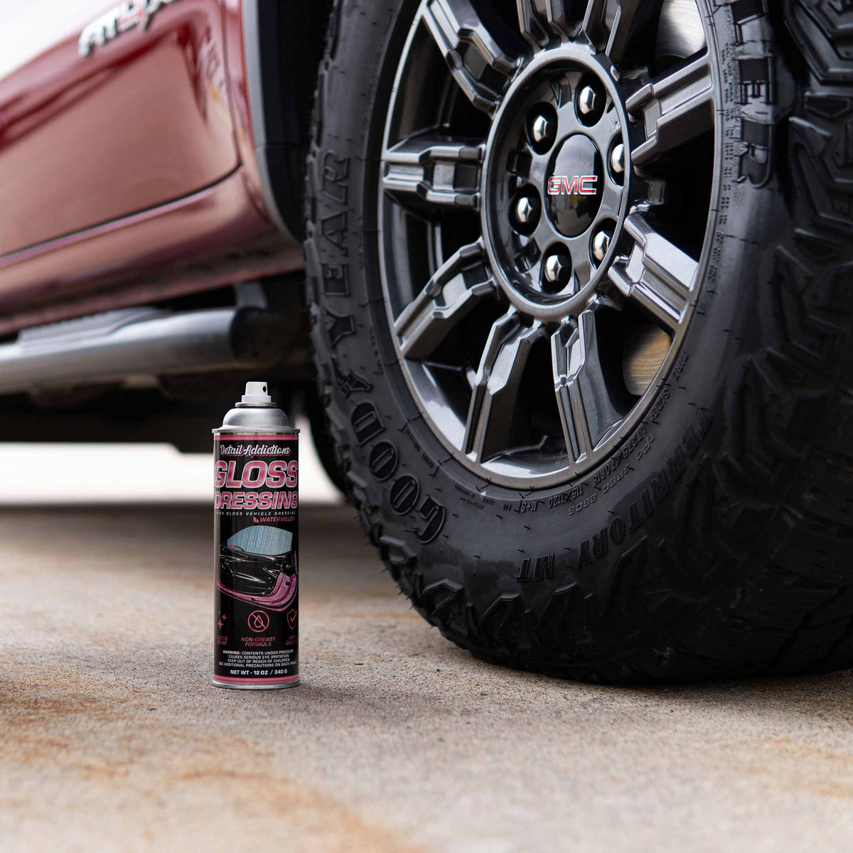 Detail Addictions Premium Gloss Dressing can beside the tire of a red pickup truck
