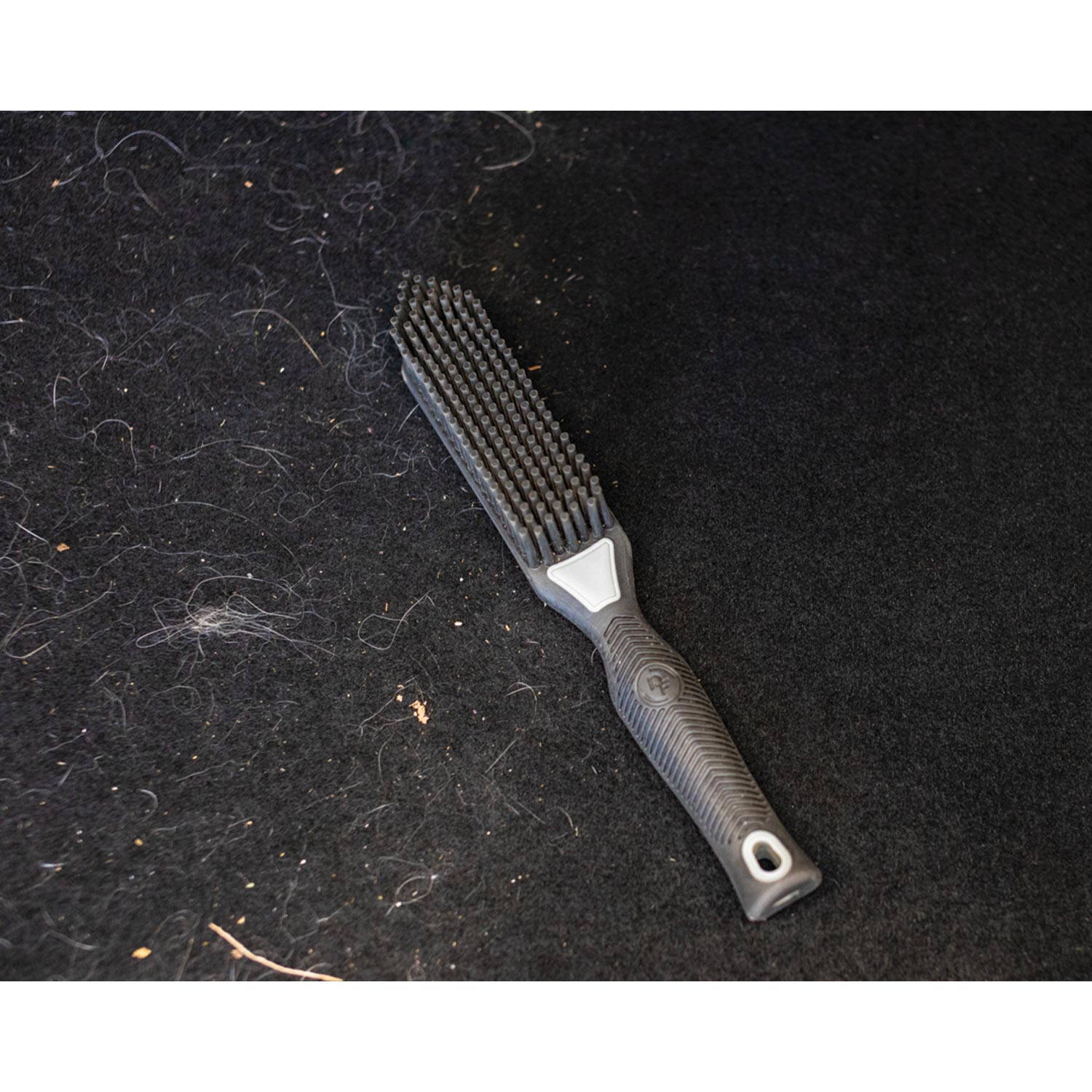 Black bristle brush on a dark pet hair fabric surface