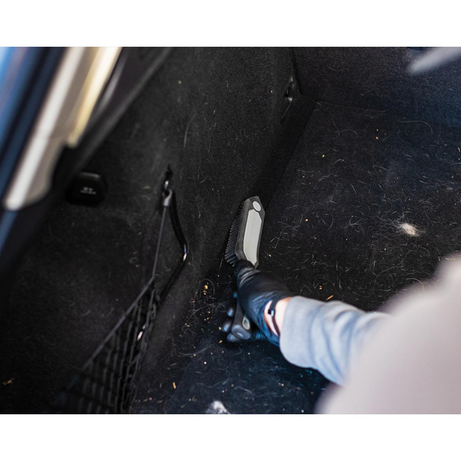 Person cleaning car interior with a pet hair brush