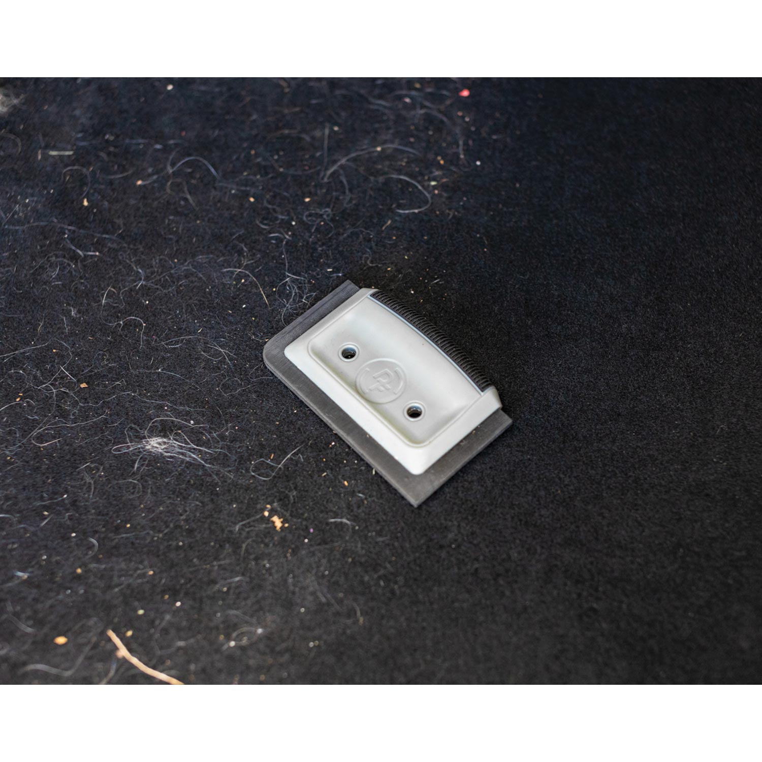 Gray and black pet hair card scraper on car fabric
